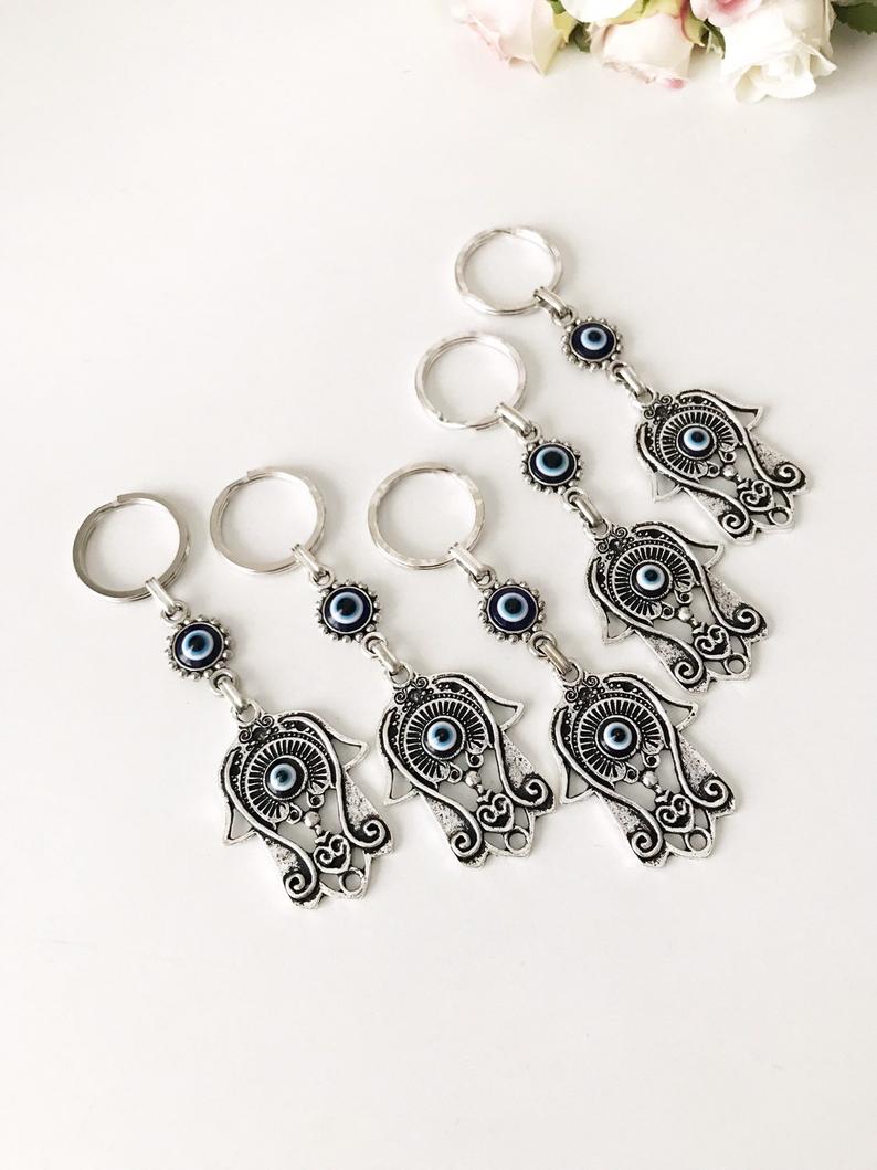 A beautiful silver hamsa keyring featuring handmade blue glass evil eye beads, symbolizing protection and good luck.