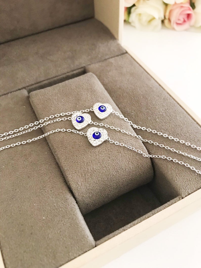 A delicate silver heart bracelet featuring an evil eye charm, elegantly designed for protection and style.