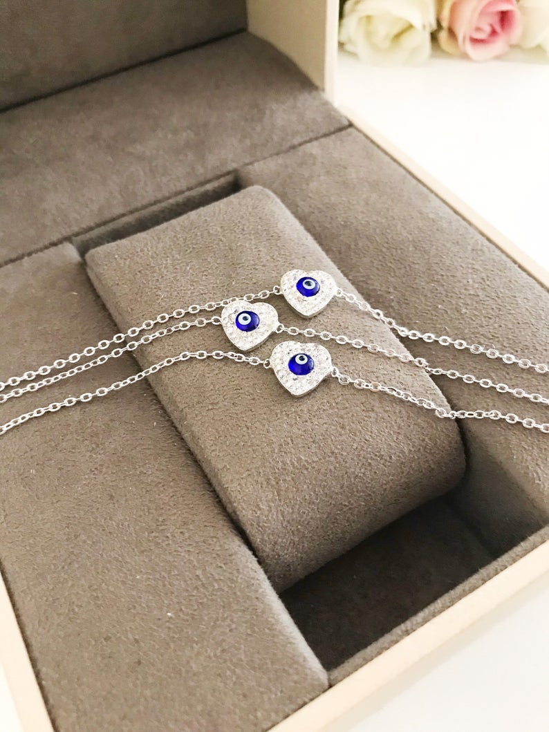 A delicate silver heart bracelet featuring an evil eye charm, elegantly designed for protection and style.