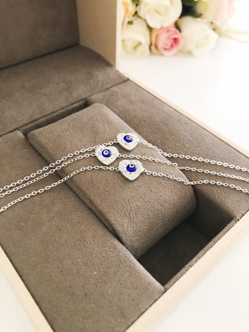 A delicate silver heart bracelet featuring an evil eye charm, elegantly designed for protection and style.