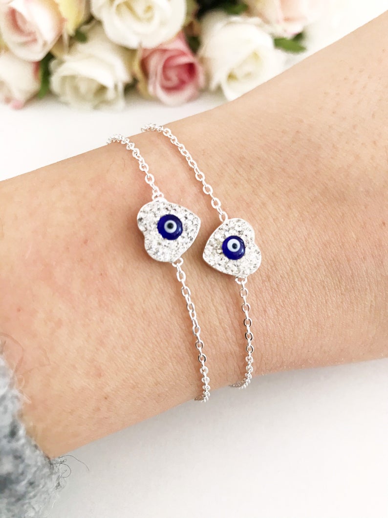 A delicate silver heart bracelet featuring an evil eye charm, elegantly designed for protection and style.