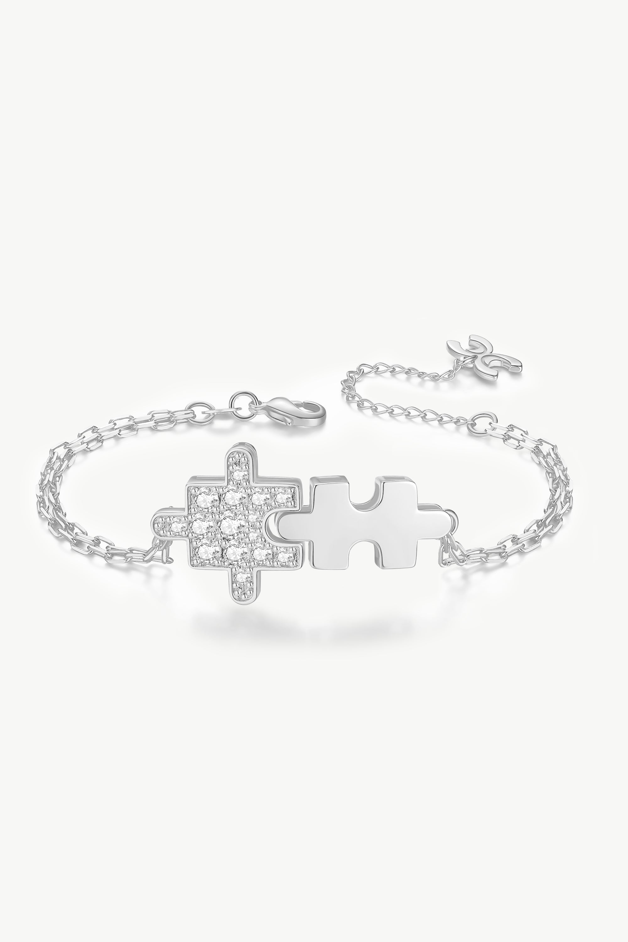 A beautiful silver bracelet featuring jigsaw puzzle-shaped charms adorned with sparkling cubic zirconia stones, showcasing its handcrafted elegance.