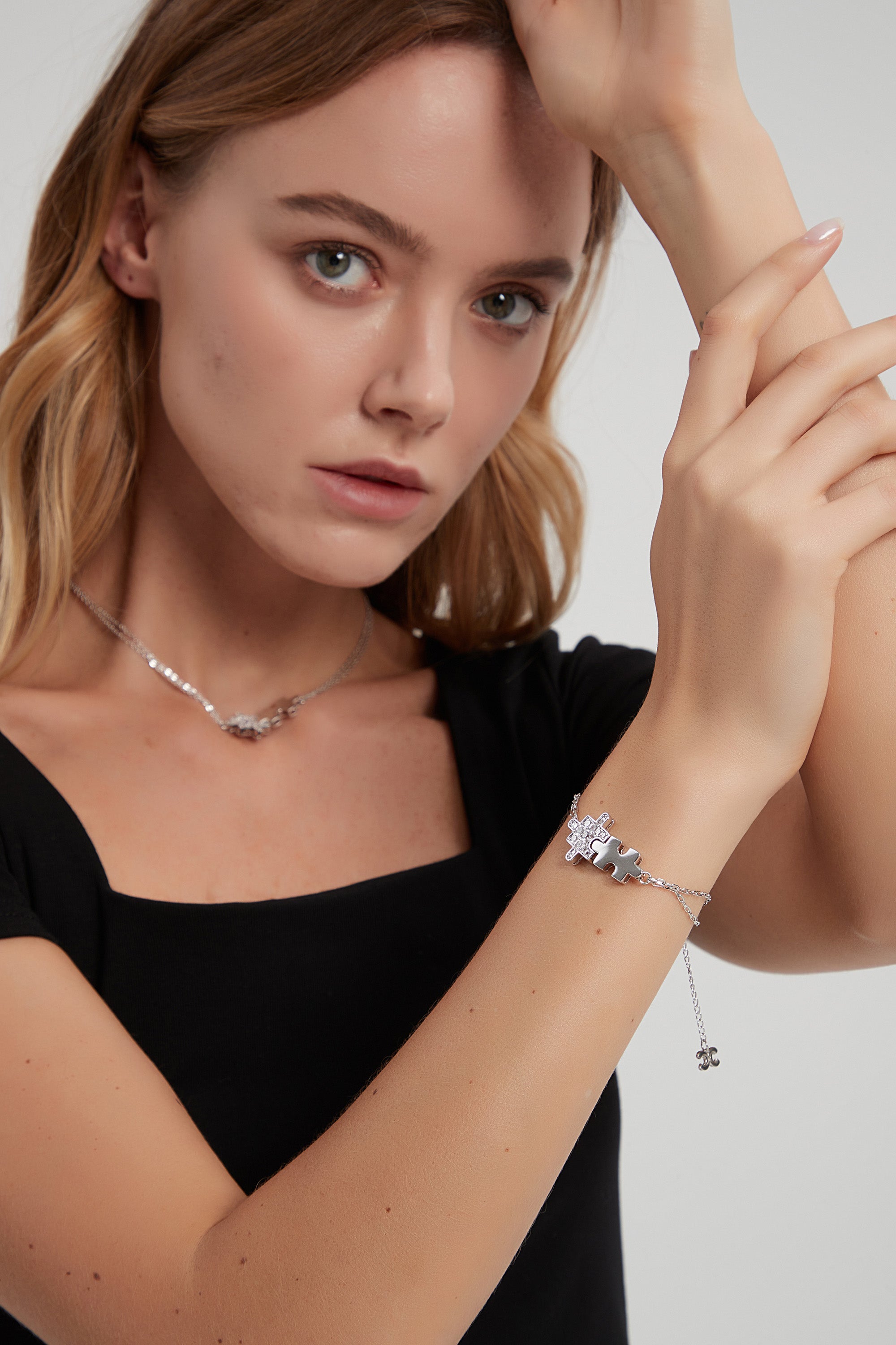 A beautiful silver bracelet featuring jigsaw puzzle-shaped charms adorned with sparkling cubic zirconia stones, showcasing its handcrafted elegance.