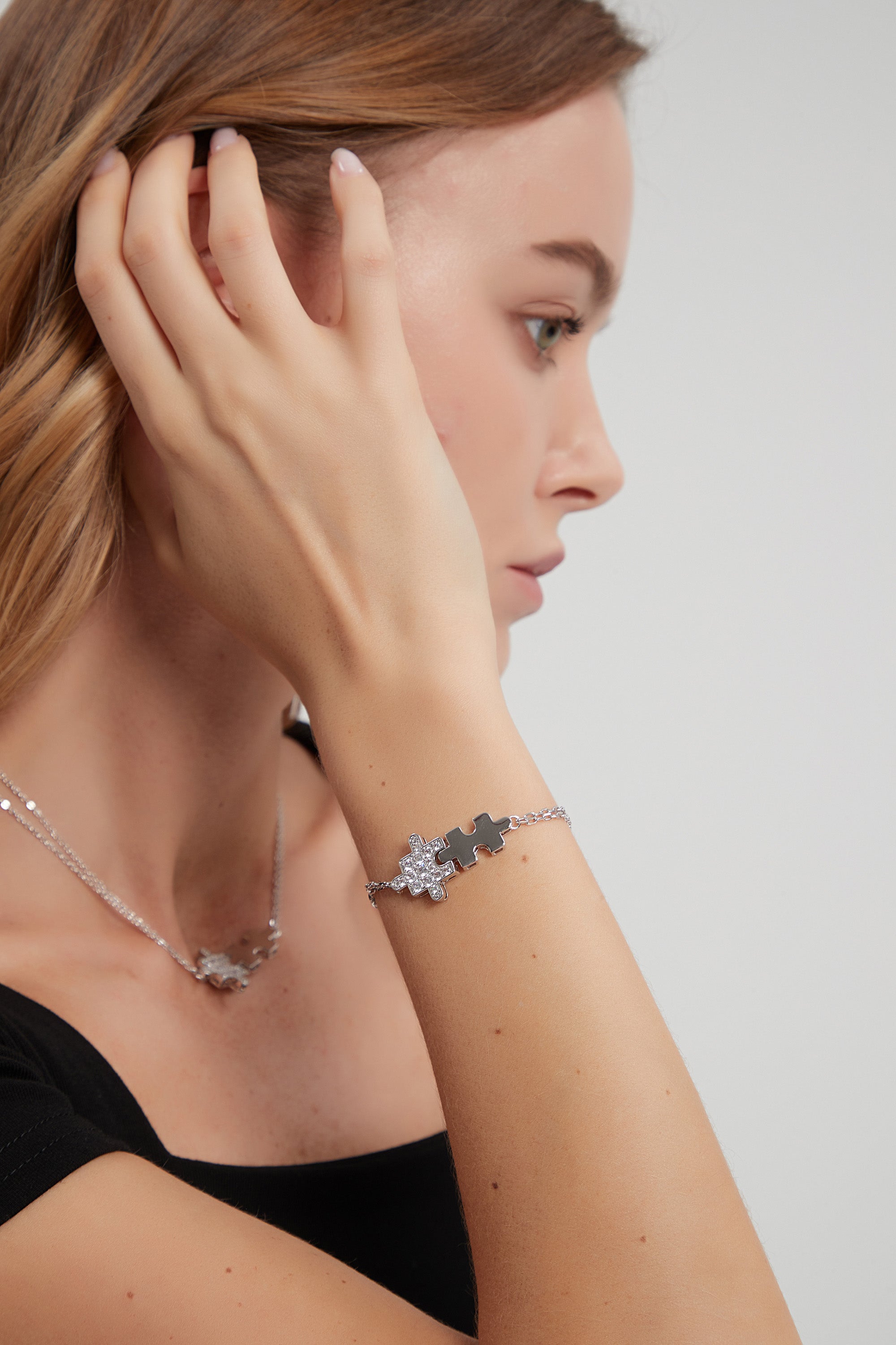 A beautiful silver bracelet featuring jigsaw puzzle-shaped charms adorned with sparkling cubic zirconia stones, showcasing its handcrafted elegance.