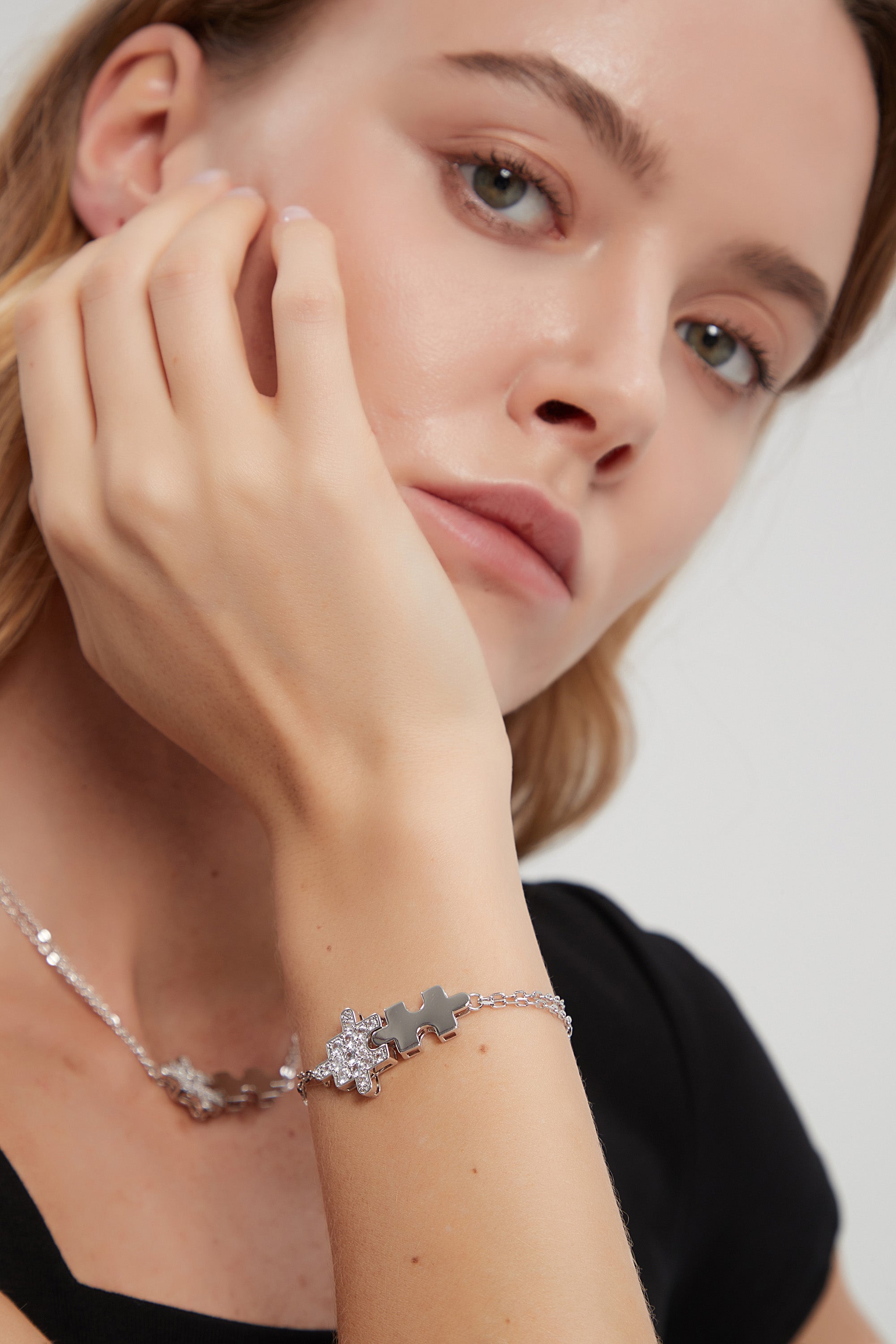 A beautiful silver bracelet featuring jigsaw puzzle-shaped charms adorned with sparkling cubic zirconia stones, showcasing its handcrafted elegance.