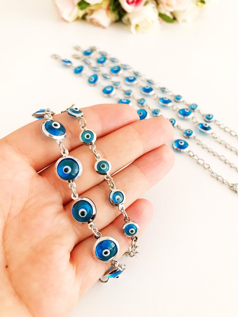 Silver link chain bracelet adorned with clear turquoise evil eye beads, showcasing a blend of elegance and cultural significance.