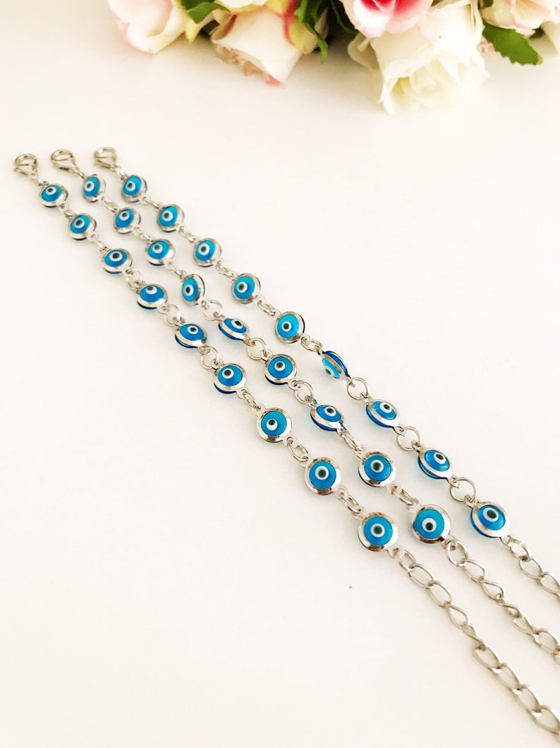 Silver link chain bracelet adorned with clear turquoise evil eye beads, showcasing a blend of elegance and cultural significance.