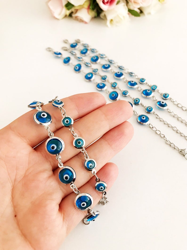 Silver link chain bracelet adorned with clear turquoise evil eye beads, showcasing a blend of elegance and cultural significance.