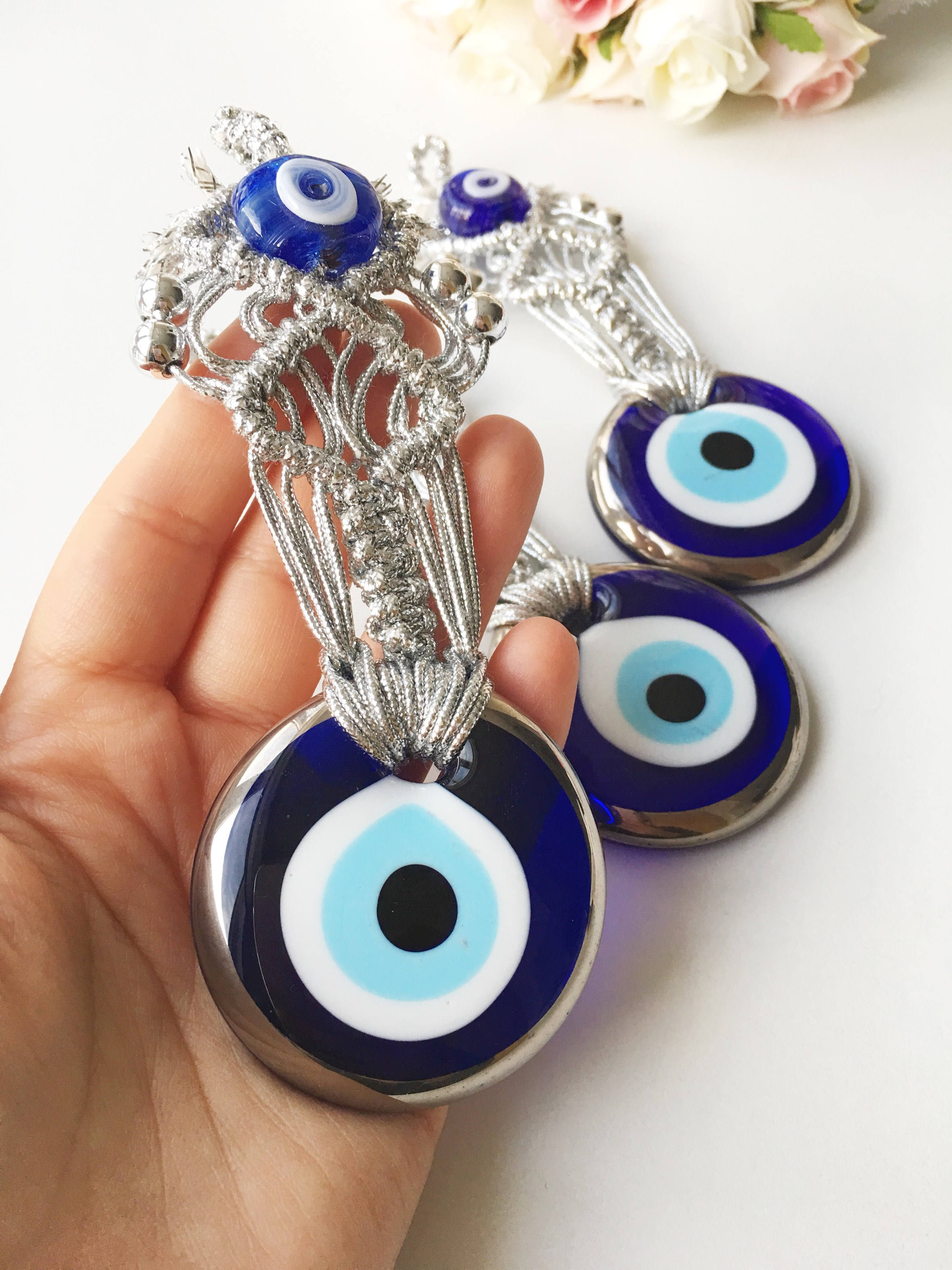 Silver Macrame Evil Eye Charm wall hanging with intricate design and blue evil eye bead.