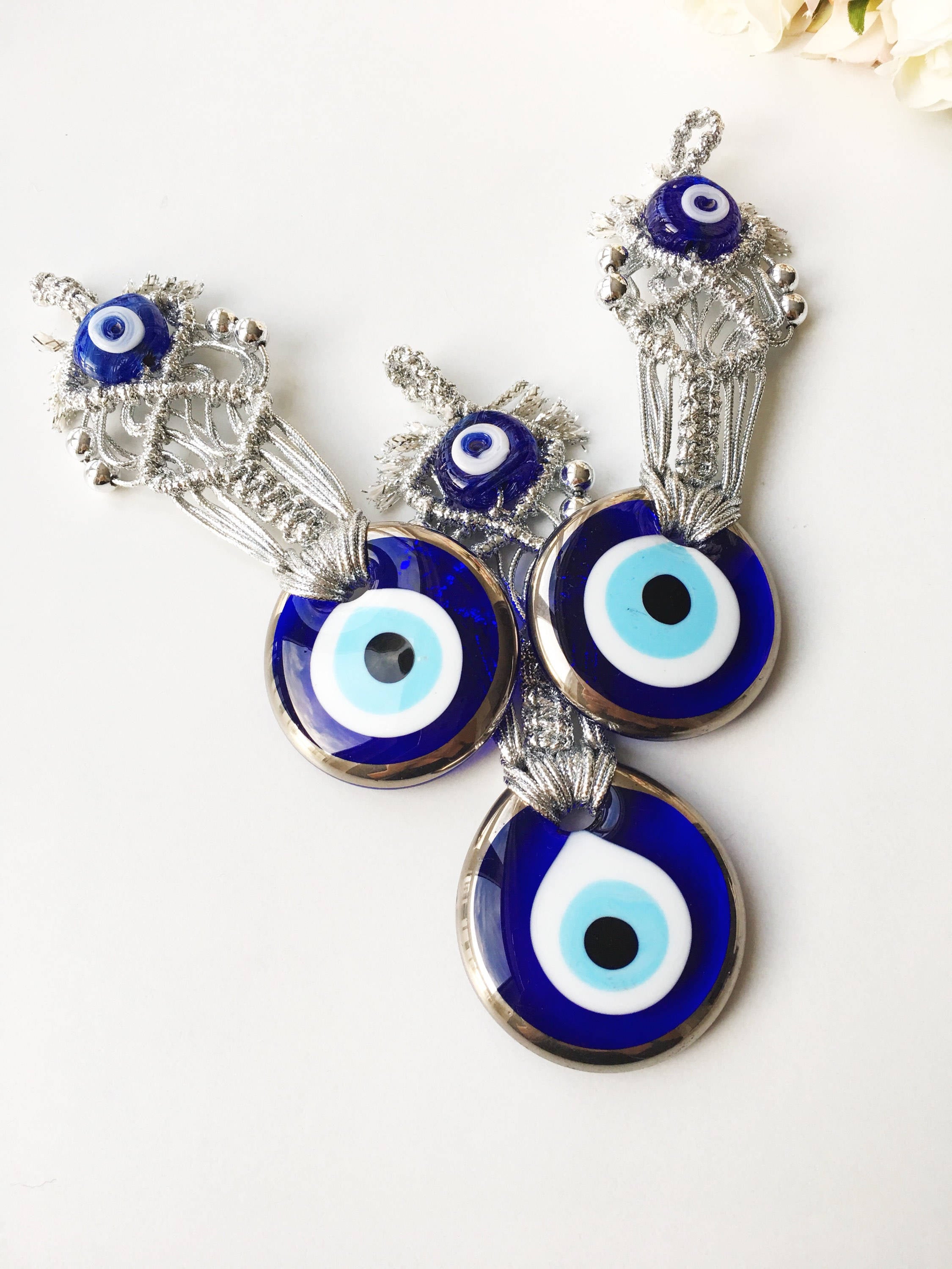 Silver Macrame Evil Eye Charm wall hanging with intricate design and blue evil eye bead.