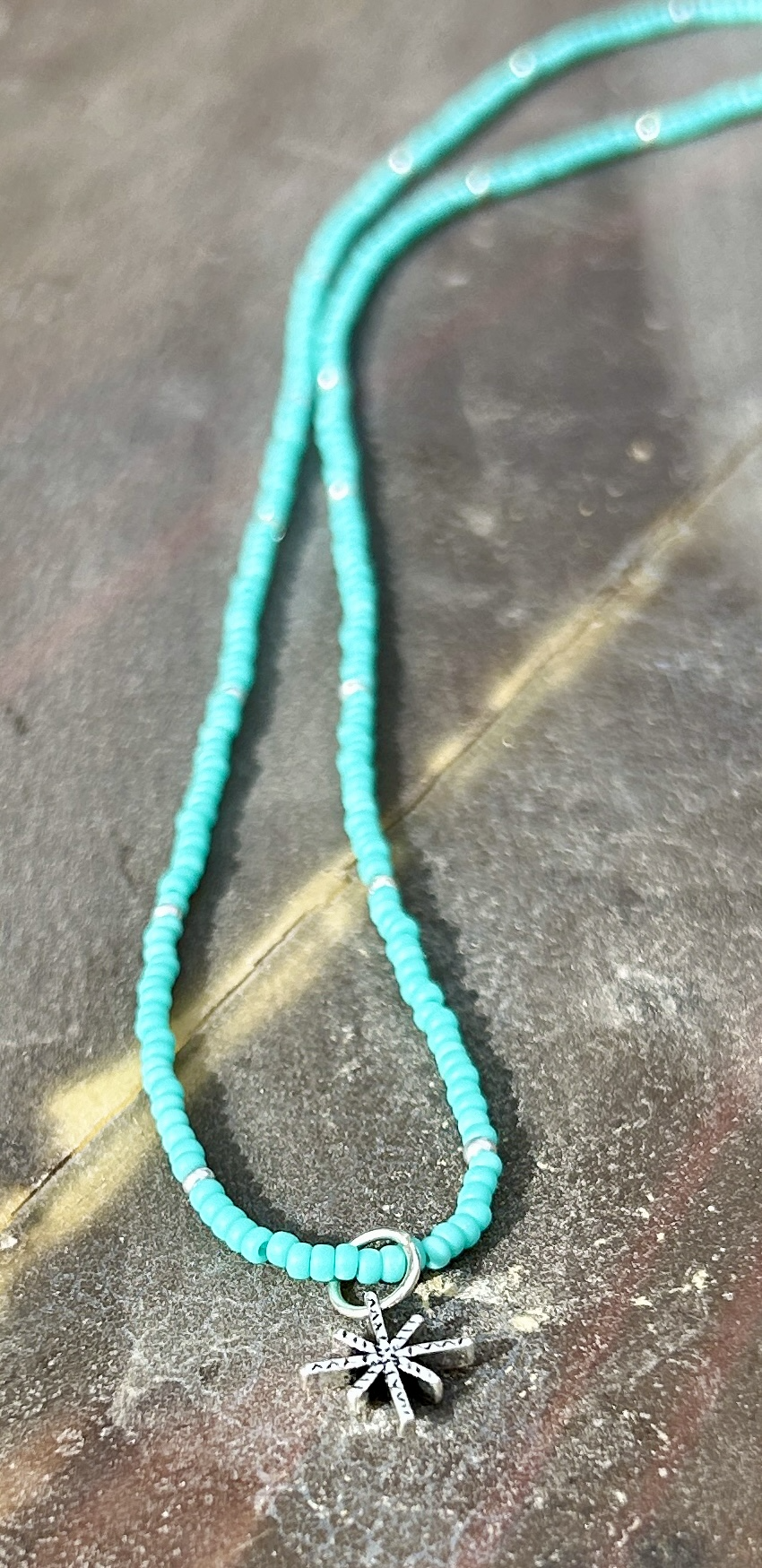 Silver Starburst Bling Turquoise Stretchy Seed Bead Necklace featuring turquoise Czech glass beads, silver metallic beads, and a starburst charm.