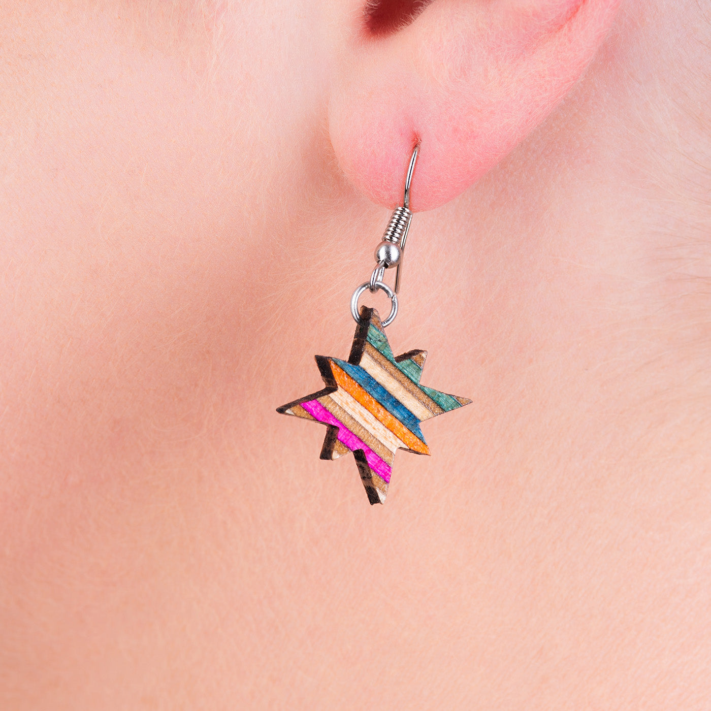 A pair of handcrafted earrings made from recycled skateboard materials, showcasing unique colors and patterns.