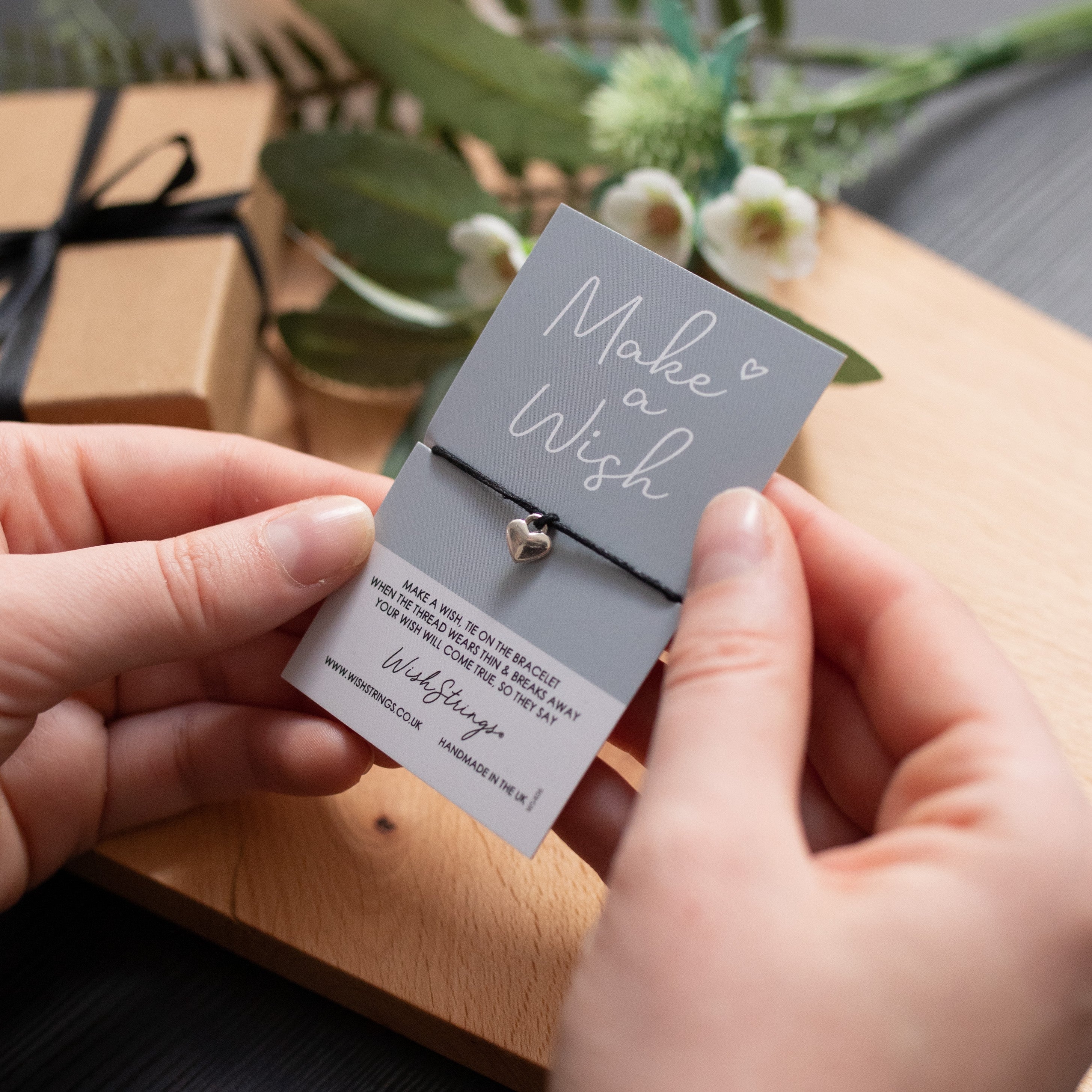 A delicate Sister Merry Christmas Wish Bracelet featuring a star-shaped charm on a waxed cotton cord, accompanied by an inspirational wish card.