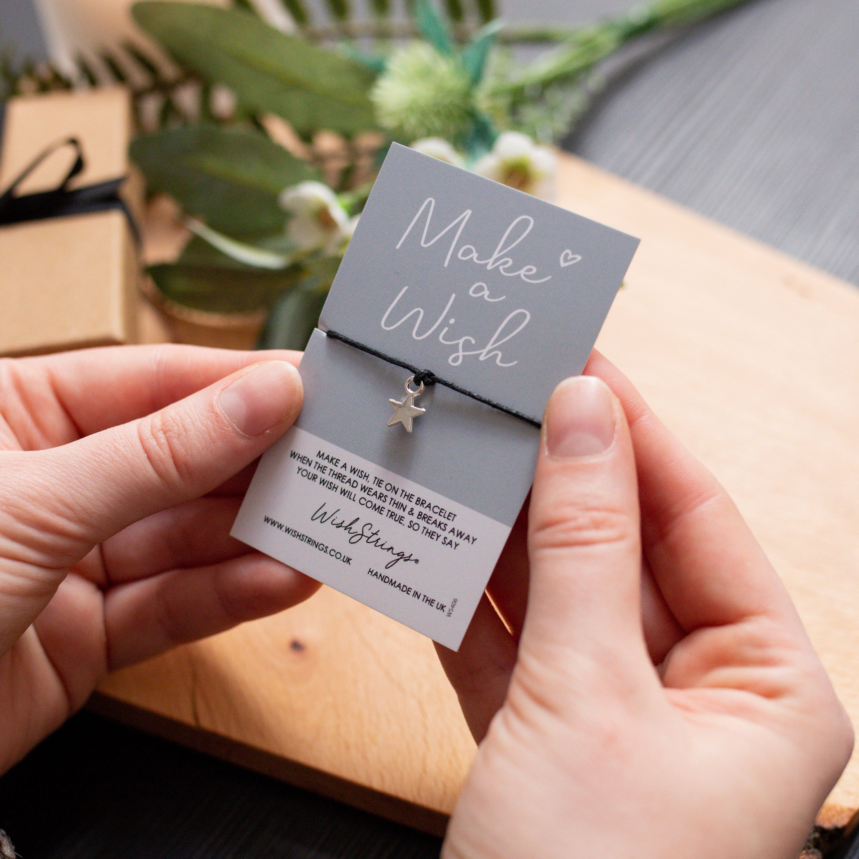 A delicate Sister Merry Christmas Wish Bracelet featuring a star-shaped charm on a waxed cotton cord, accompanied by an inspirational wish card.