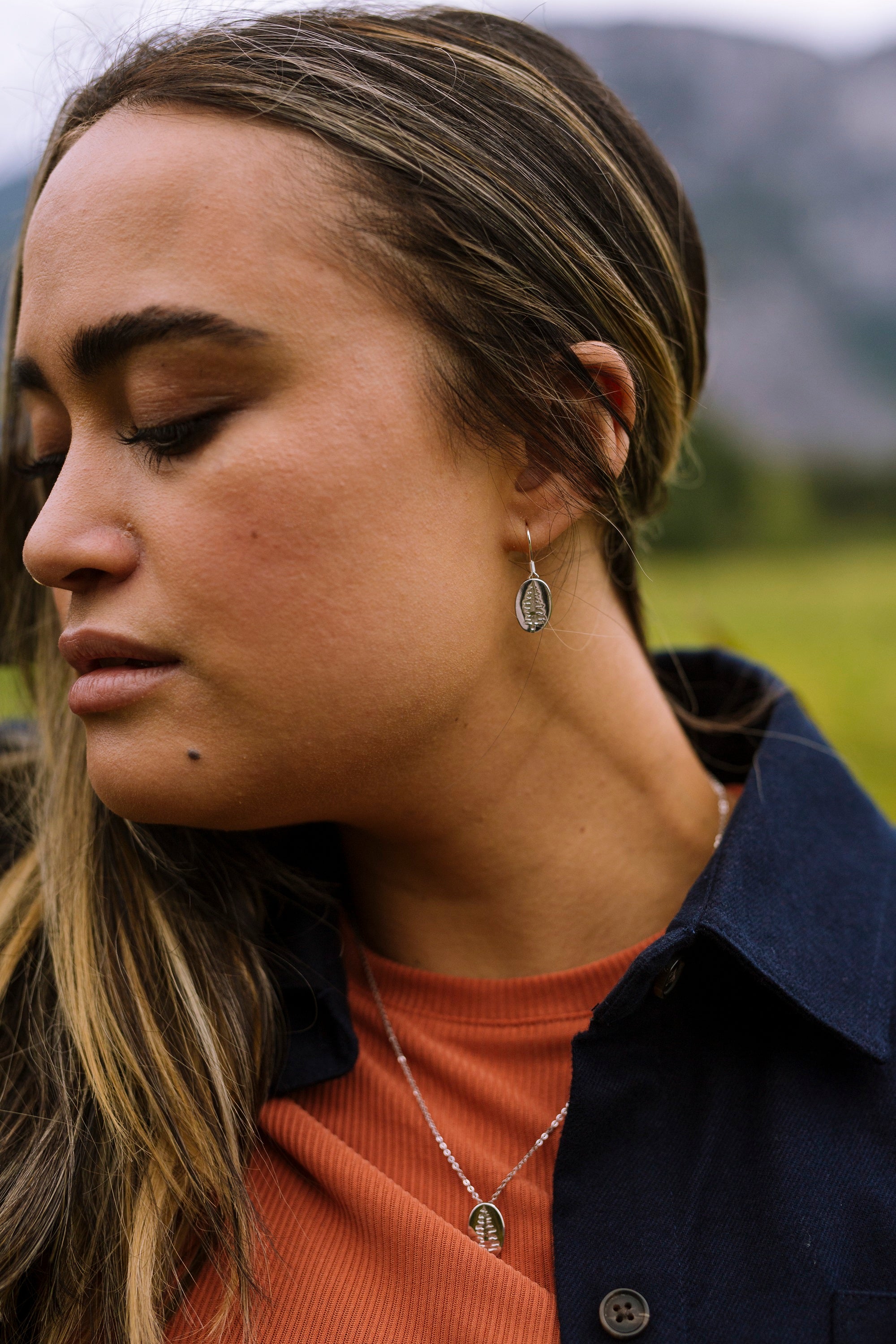 Sterling silver Sitka tree earrings in oval shape, showcasing intricate coastal designs.