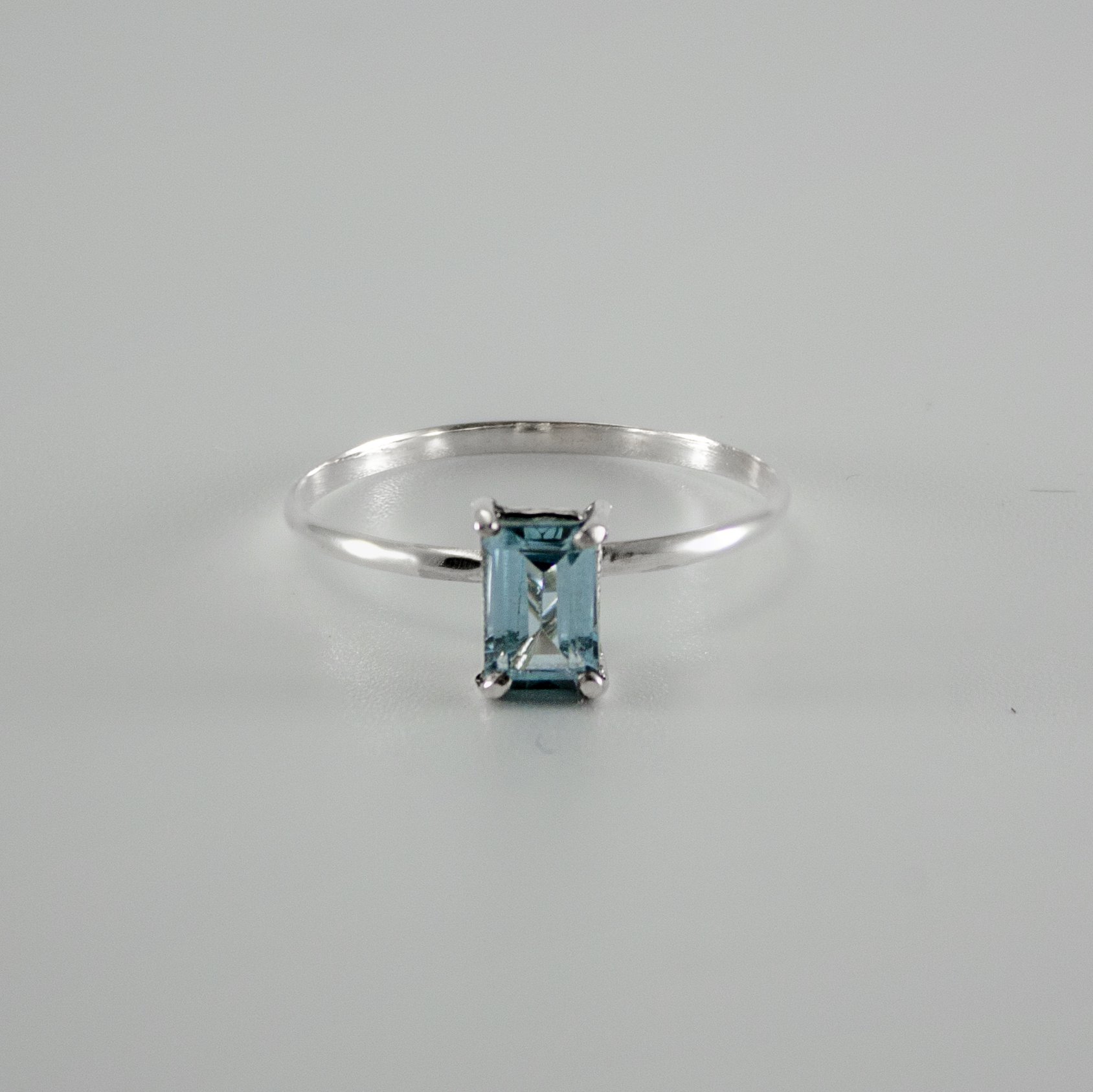 Sky Blue Topaz Four Prong Solitaire Ring in sterling silver, showcasing a vibrant blue gemstone set in a delicate band.