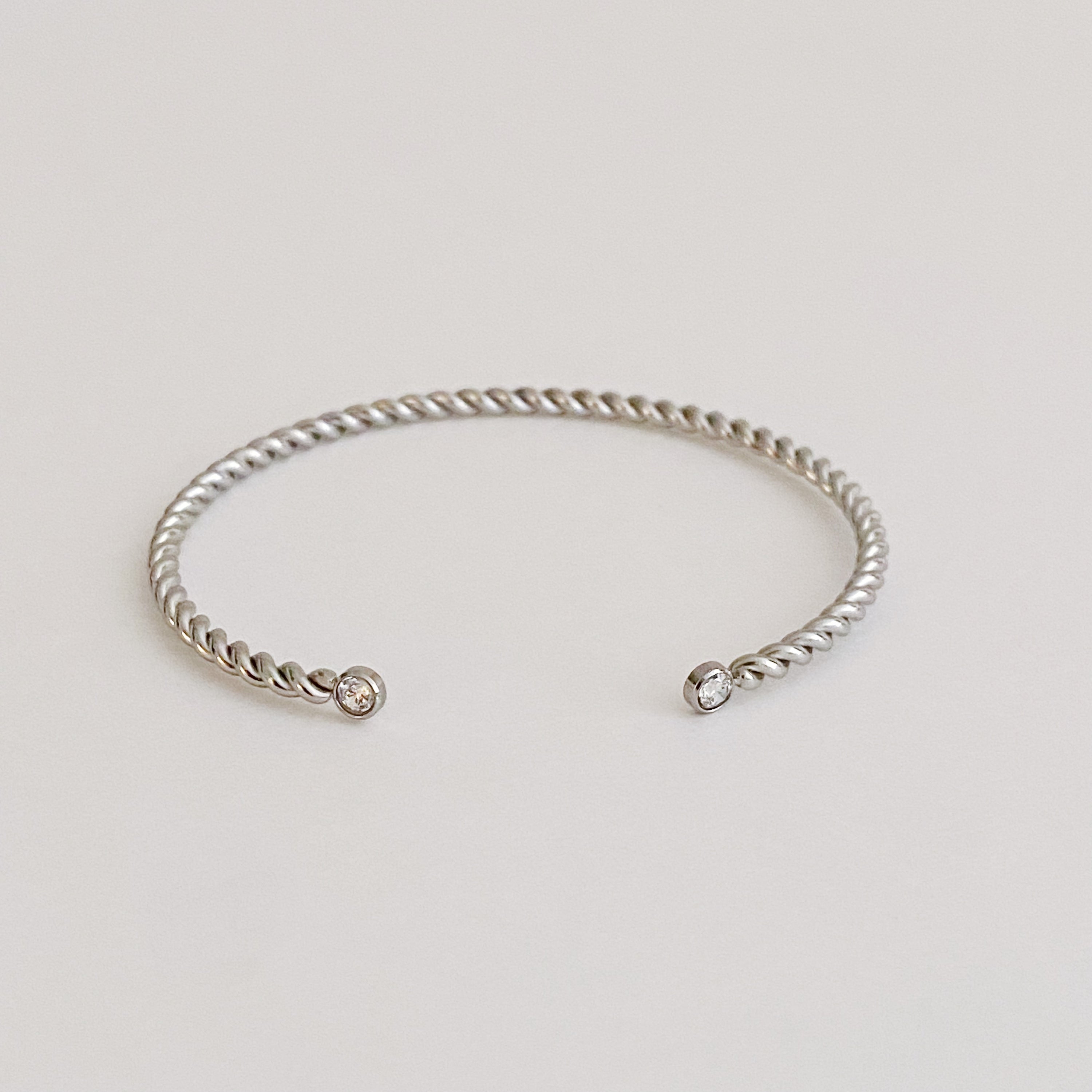 Slim and cabled open bangle bracelet with sparkly stones, showcasing a flexible design and elegant gold finish.