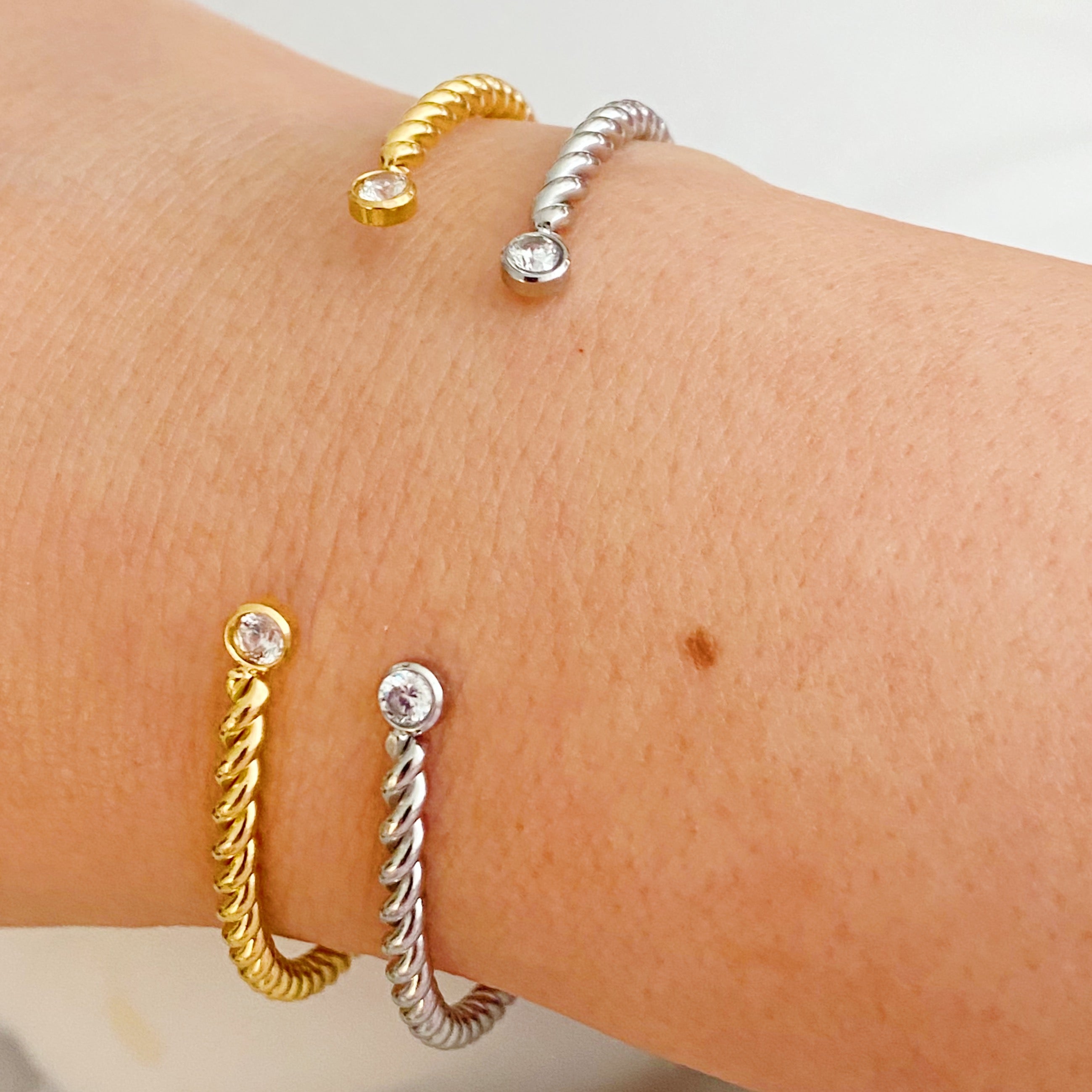 Slim and cabled open bangle bracelet with sparkly stones, showcasing a flexible design and elegant gold finish.