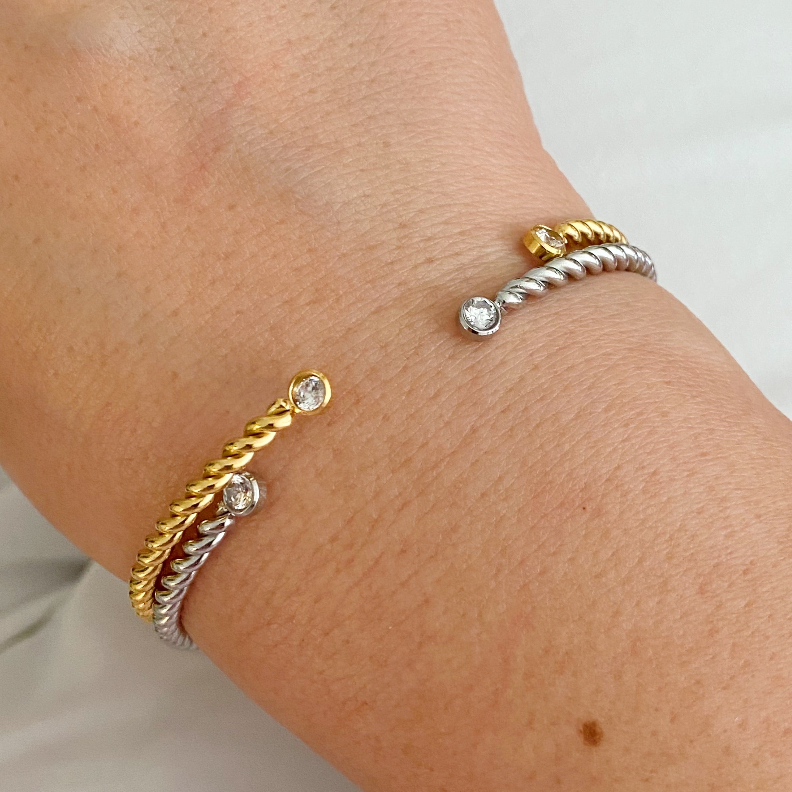 Slim and cabled open bangle bracelet with sparkly stones, showcasing a flexible design and elegant gold finish.