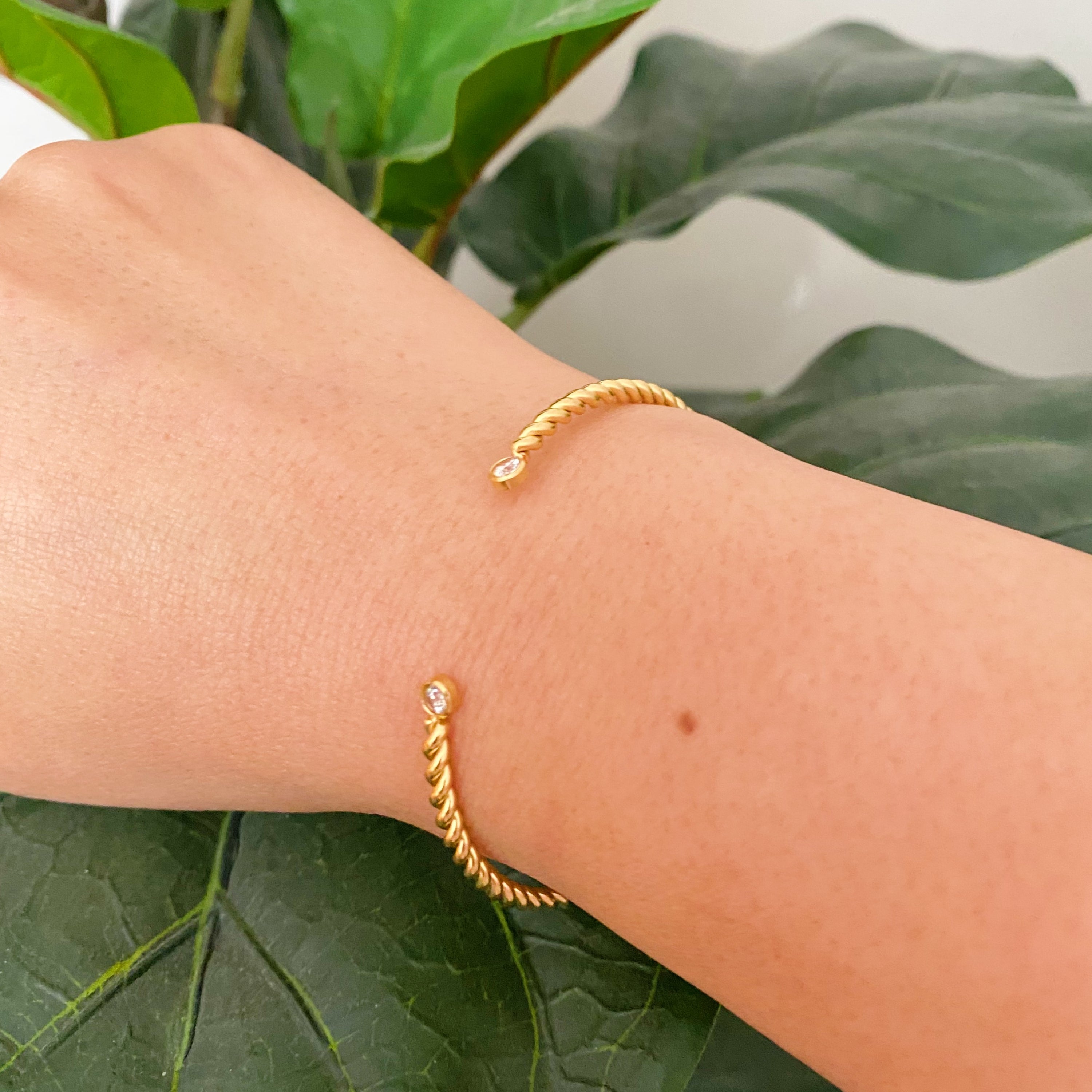 Slim and cabled open bangle bracelet with sparkly stones, showcasing a flexible design and elegant gold finish.