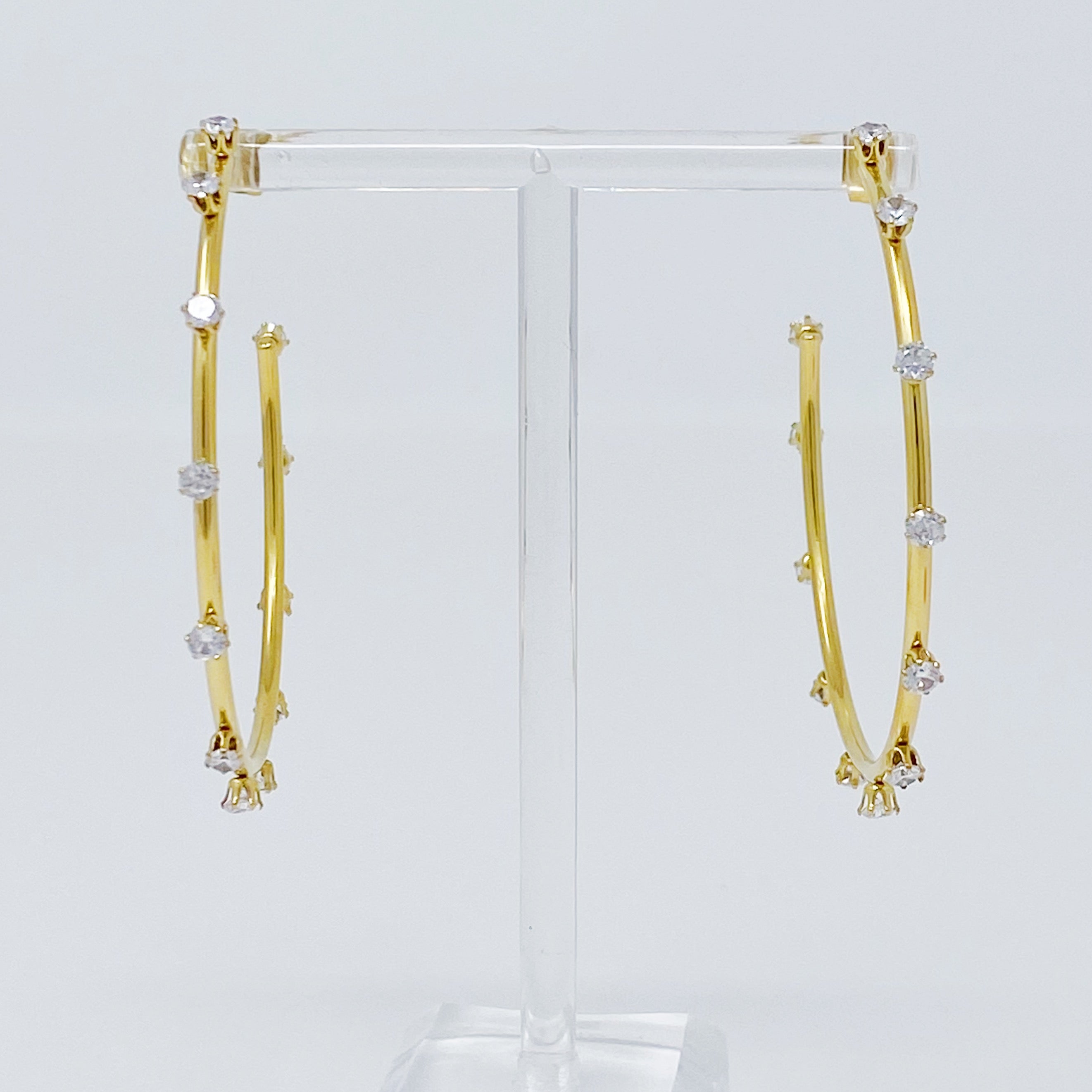 A pair of slim gold plated hoop earrings adorned with sparkling cubic zirconia jewels, showcasing elegance and style.