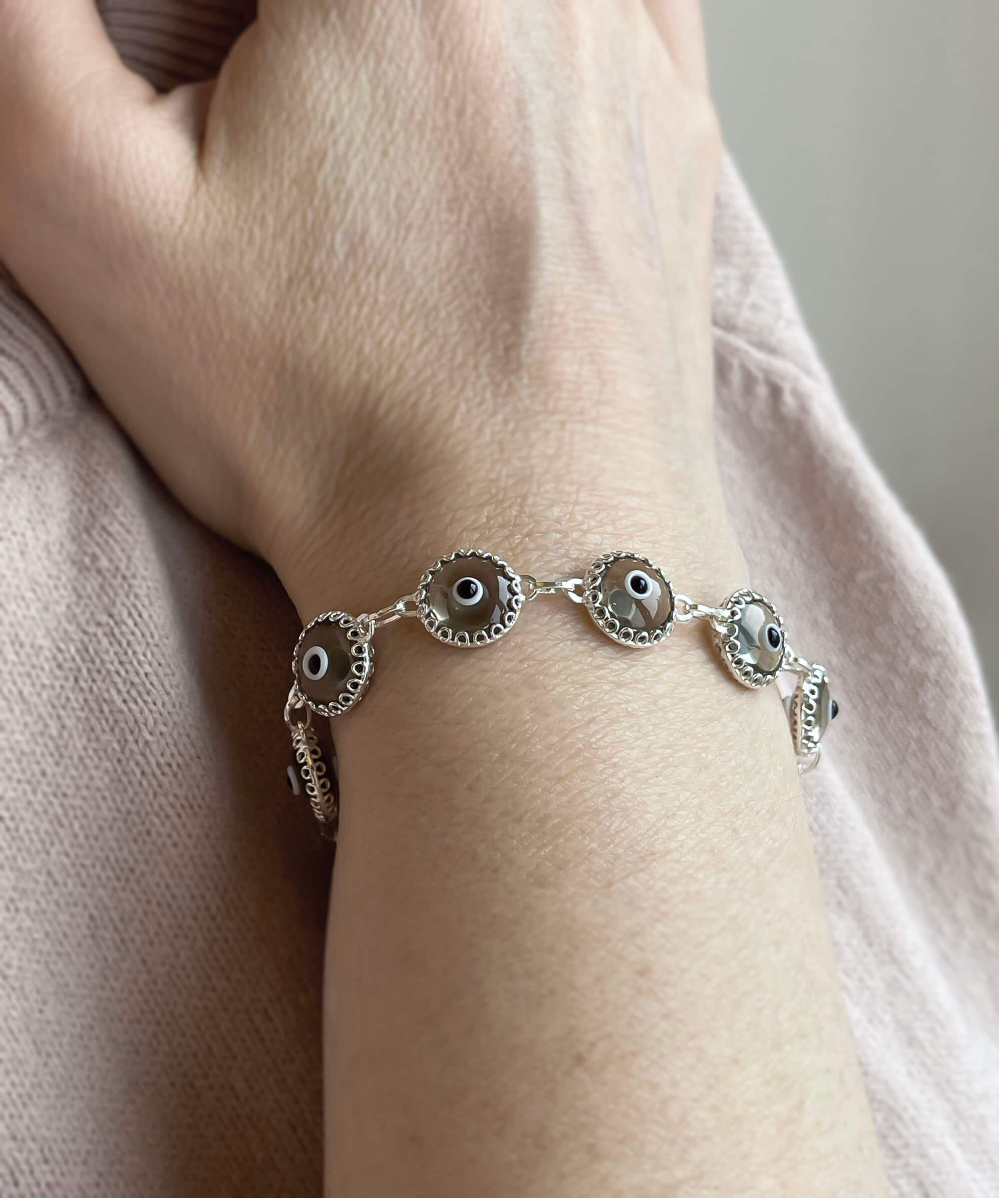 Smokey Evil Eye Woman Sterling Silver Adjustable Link Bracelet featuring a strong rolo chain and ten beads wrapped in silver prongs.