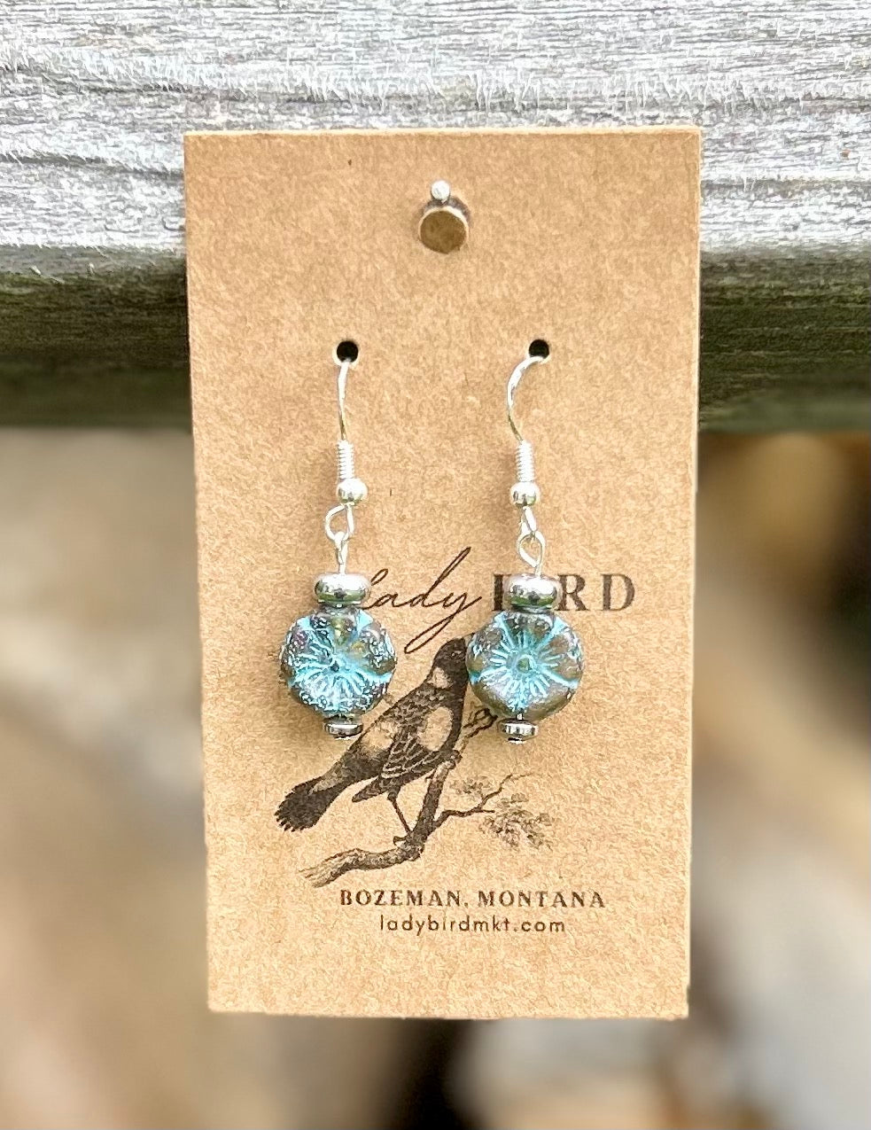 Smoky blue Czech glass hibiscus flower earrings with blue etching, showcasing a delicate floral design.