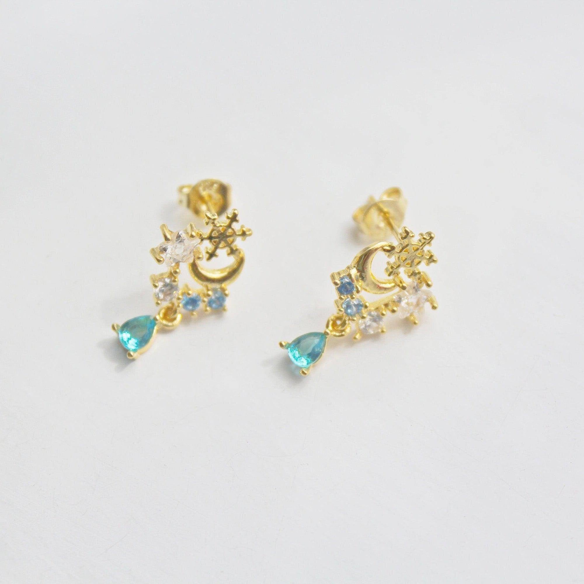 Elegant snowflake and blue crystal earrings in mini teardrop design, showcasing gold plated bronze and sterling silver materials.