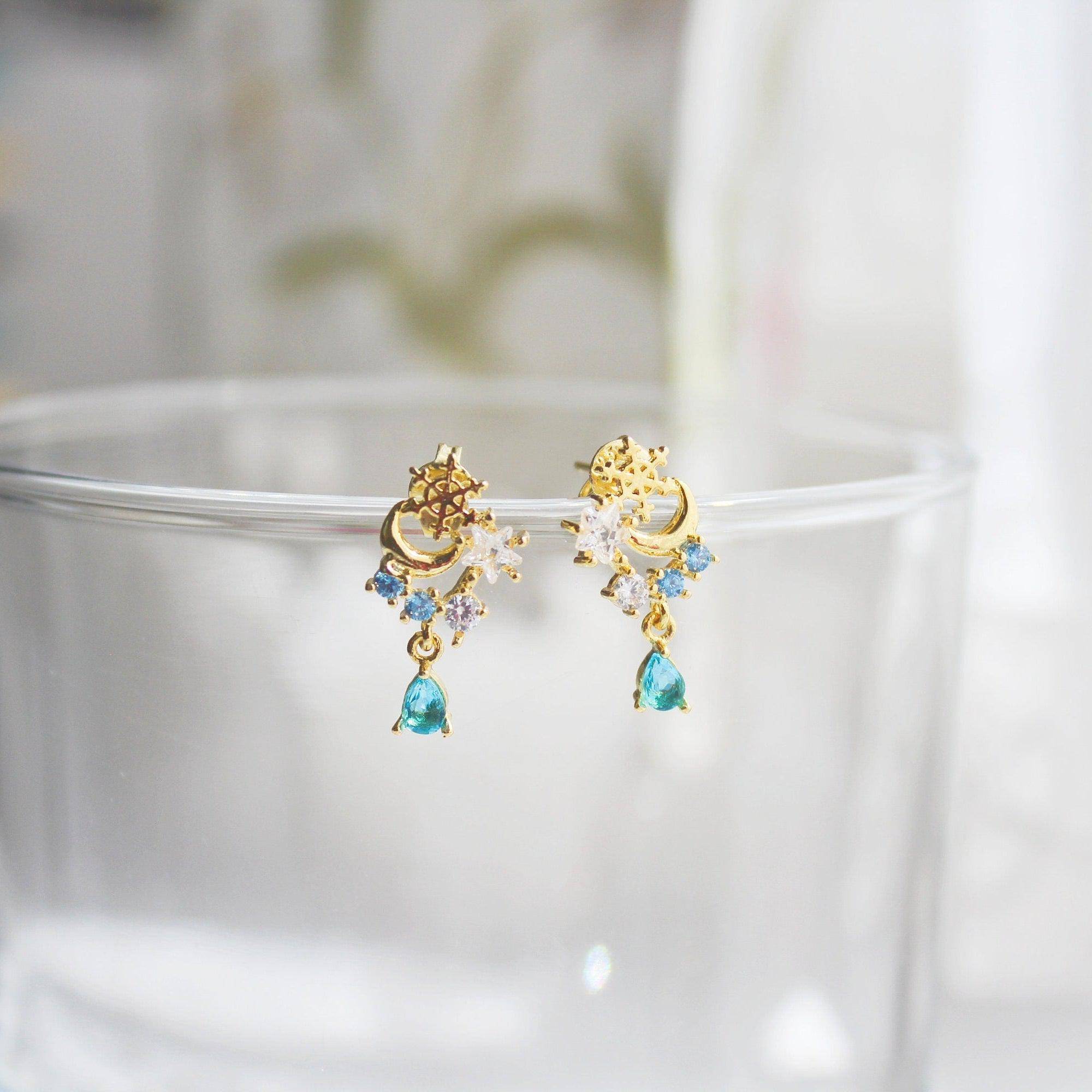 Elegant snowflake and blue crystal earrings in mini teardrop design, showcasing gold plated bronze and sterling silver materials.