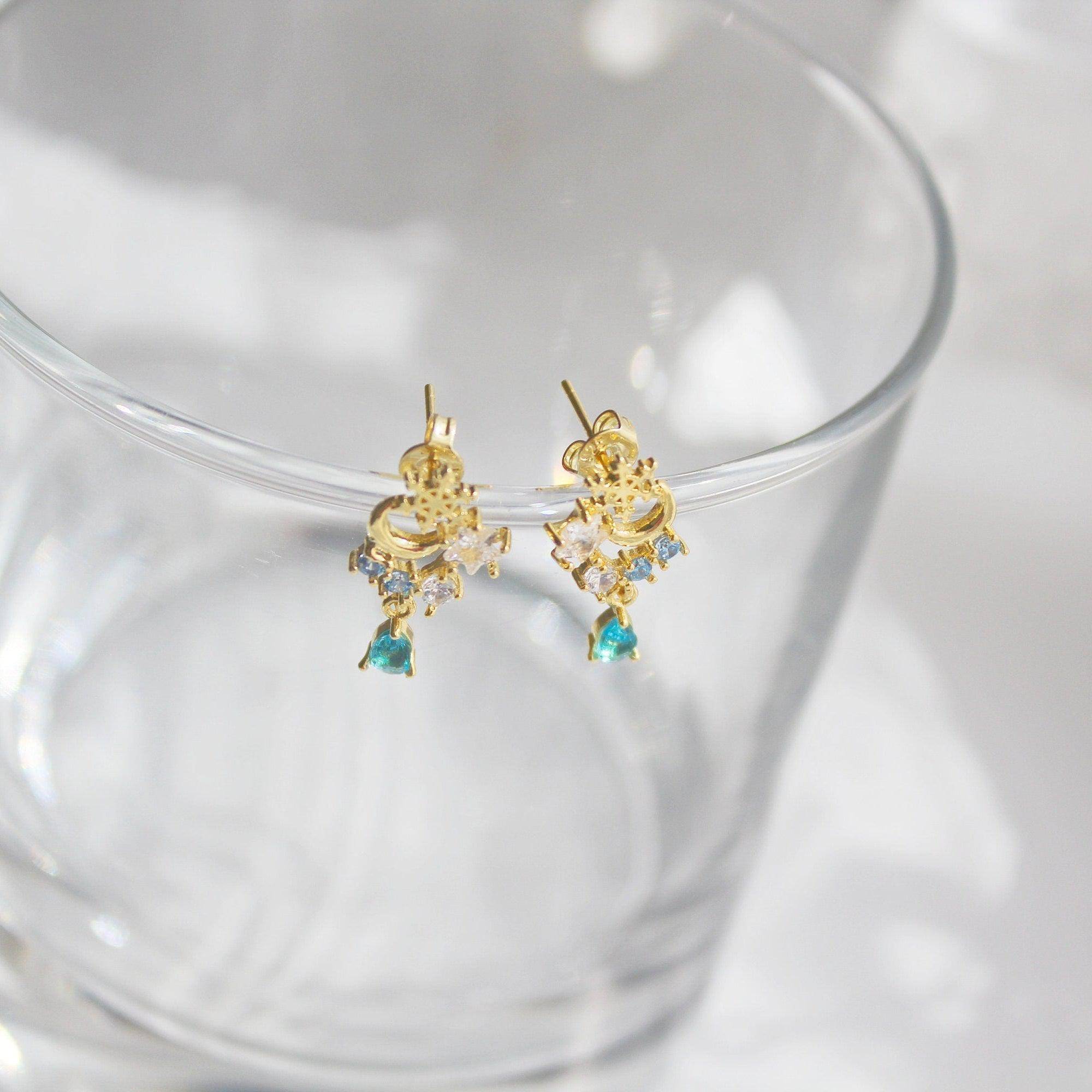 Elegant snowflake and blue crystal earrings in mini teardrop design, showcasing gold plated bronze and sterling silver materials.