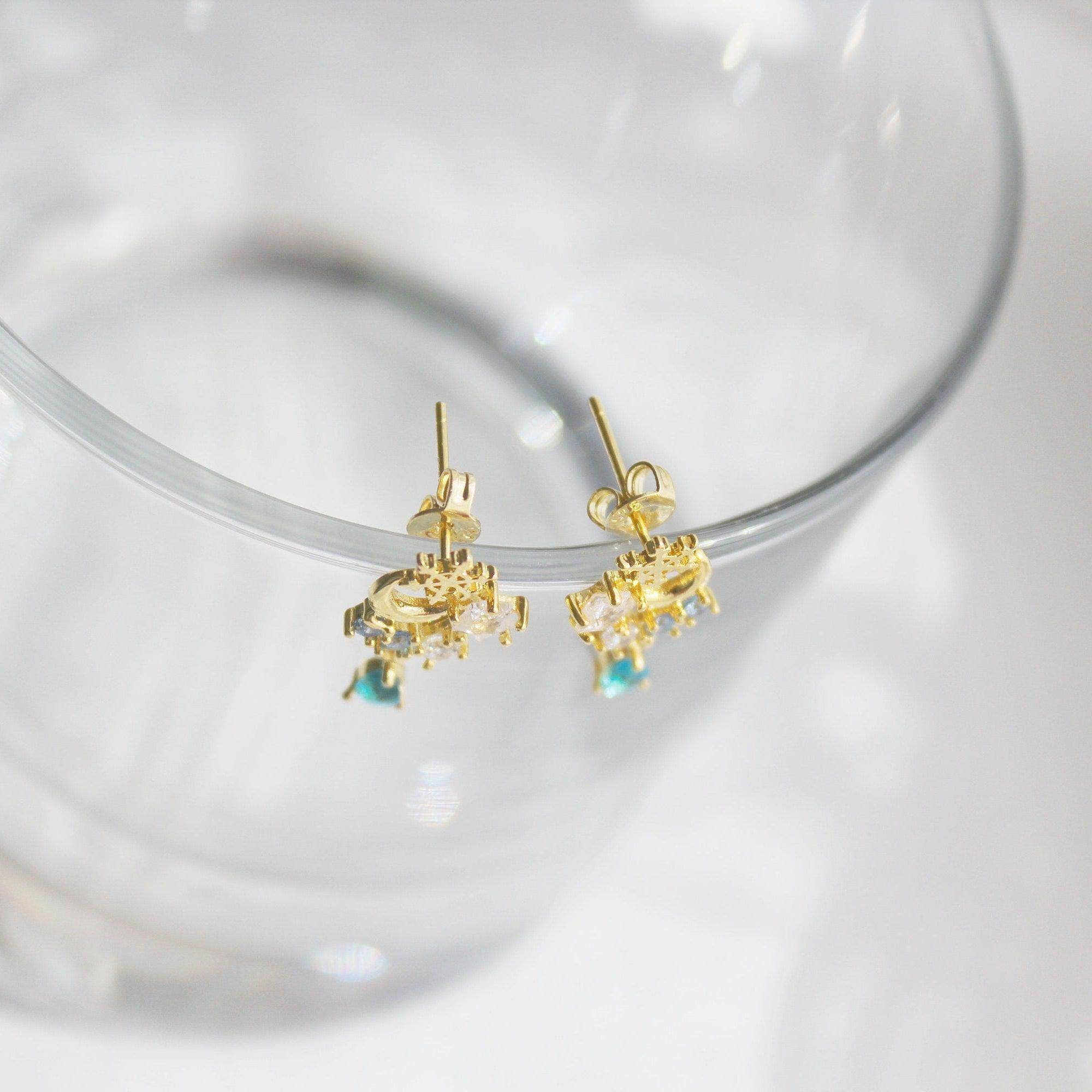 Elegant snowflake and blue crystal earrings in mini teardrop design, showcasing gold plated bronze and sterling silver materials.