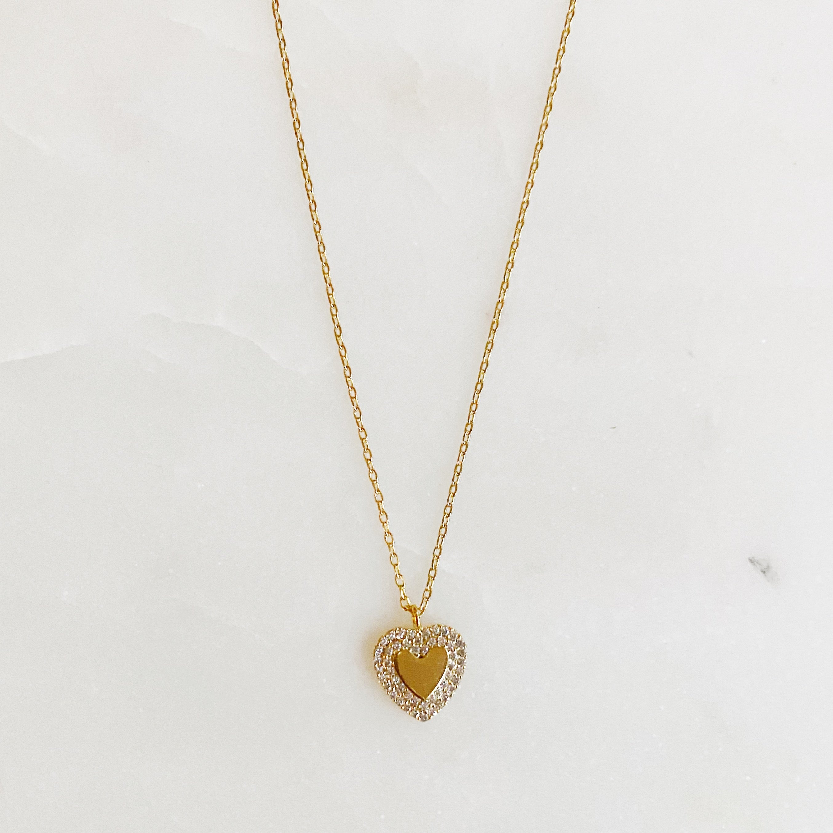 A delicate gold plated brass mini heart necklace with a 16-inch chain and a 2-inch extender, perfect for everyday wear.