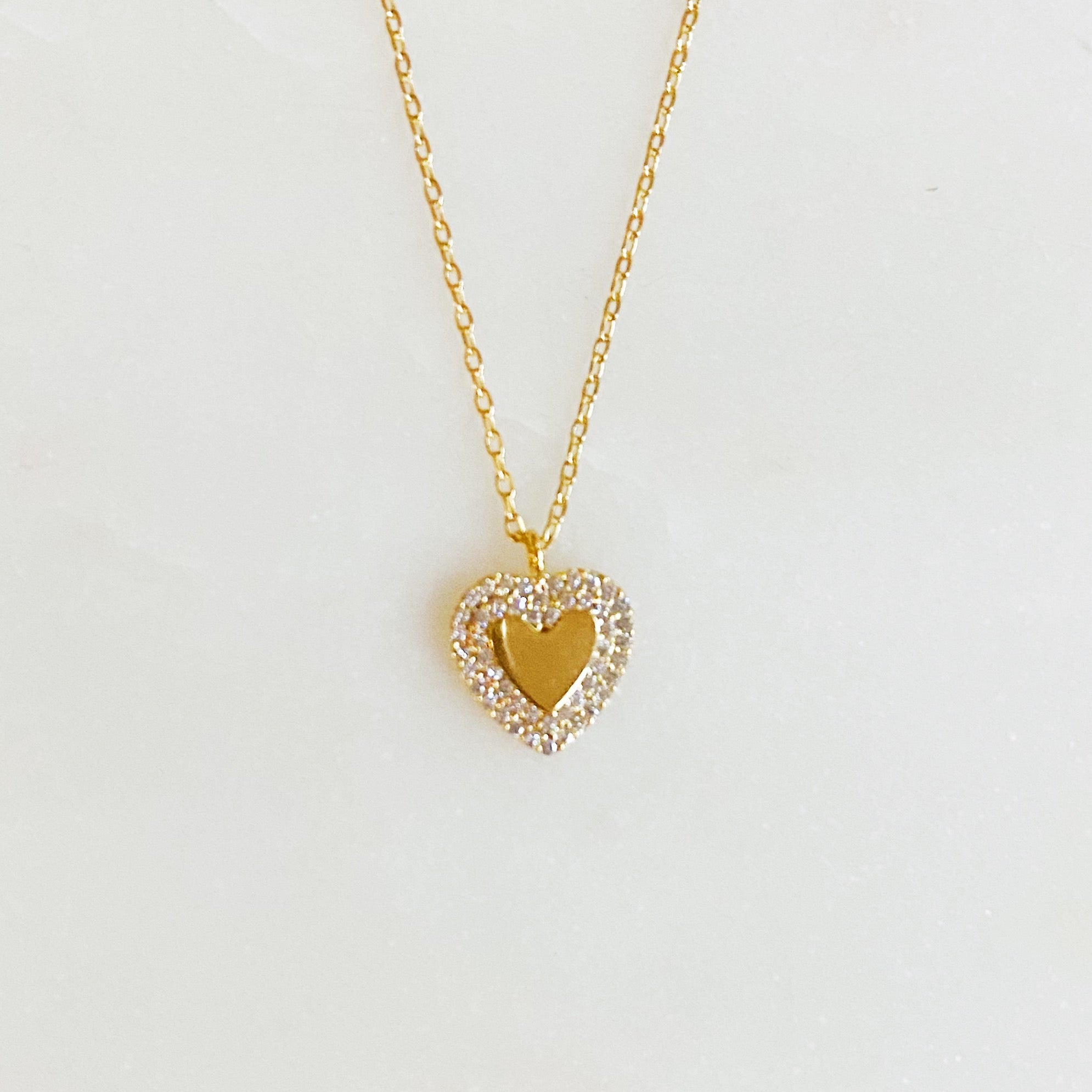 A delicate gold plated brass mini heart necklace with a 16-inch chain and a 2-inch extender, perfect for everyday wear.