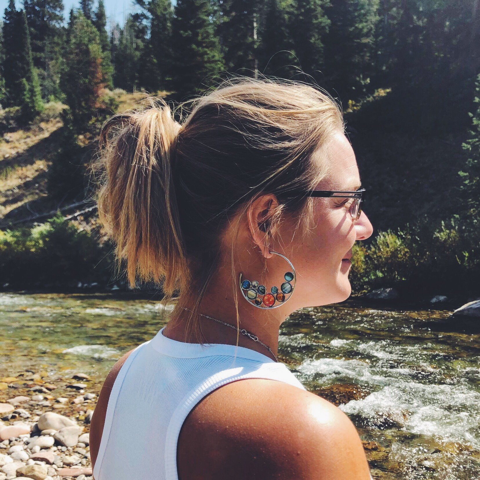 A pair of handcrafted Solar System Hoop Earrings featuring colorful planets and the Sun, set in a silver-tone design with a textured metal back.