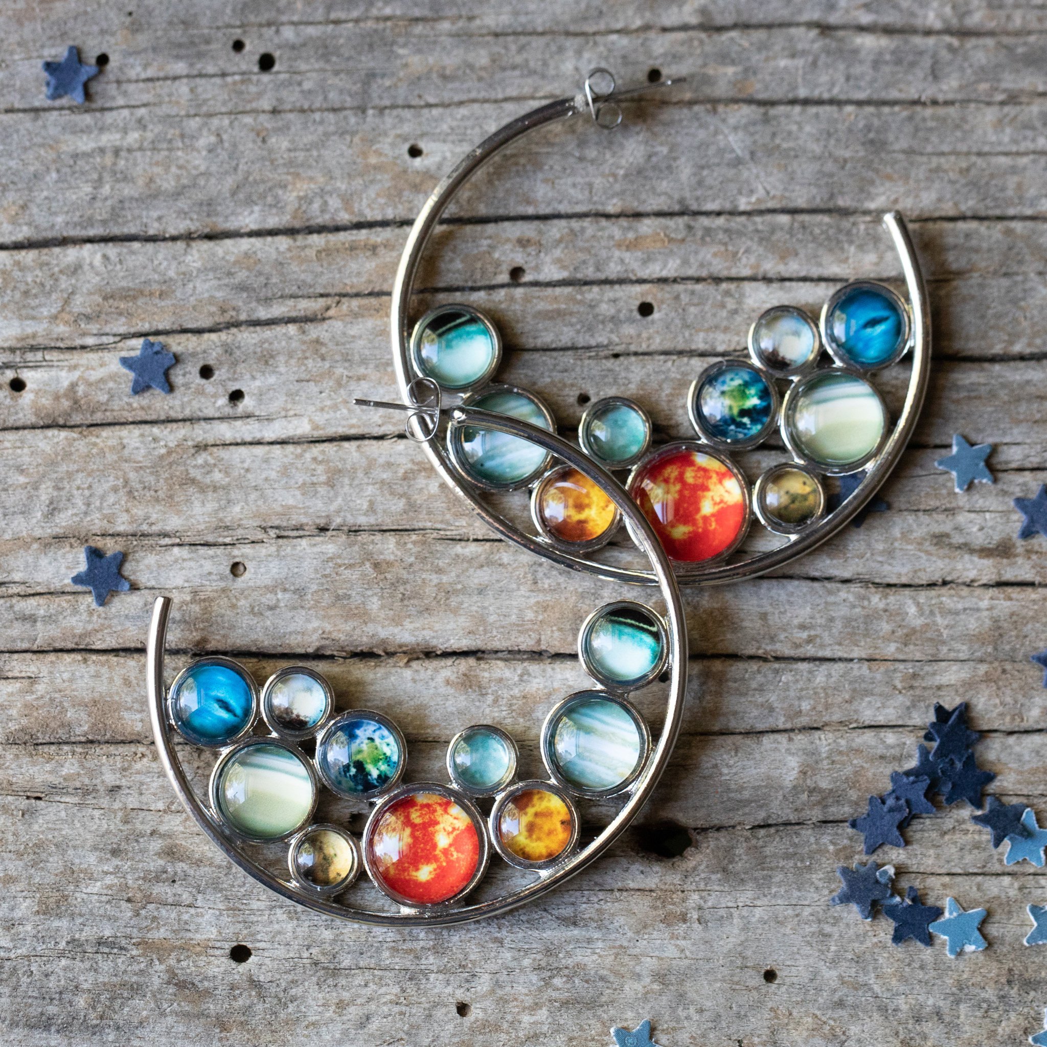 A pair of handcrafted Solar System Hoop Earrings featuring colorful planets and the Sun, set in a silver-tone design with a textured metal back.