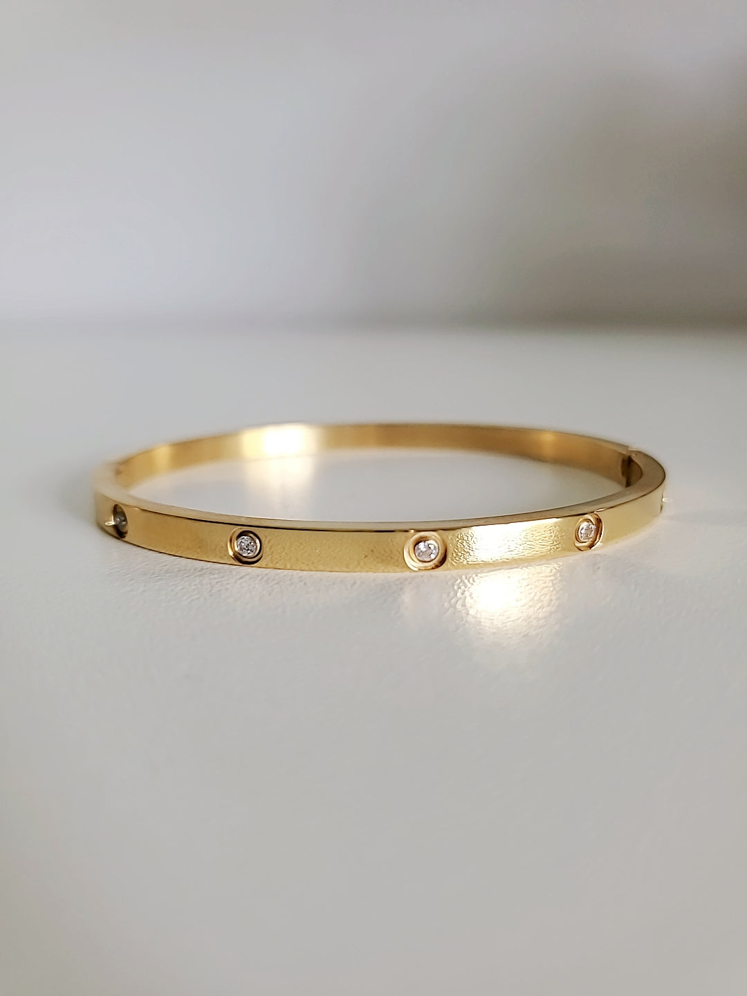 Solid Statement Bangle made of 316L Stainless Steel with 18K Gold plating and simulated diamonds, showcasing an elegant oval shape.