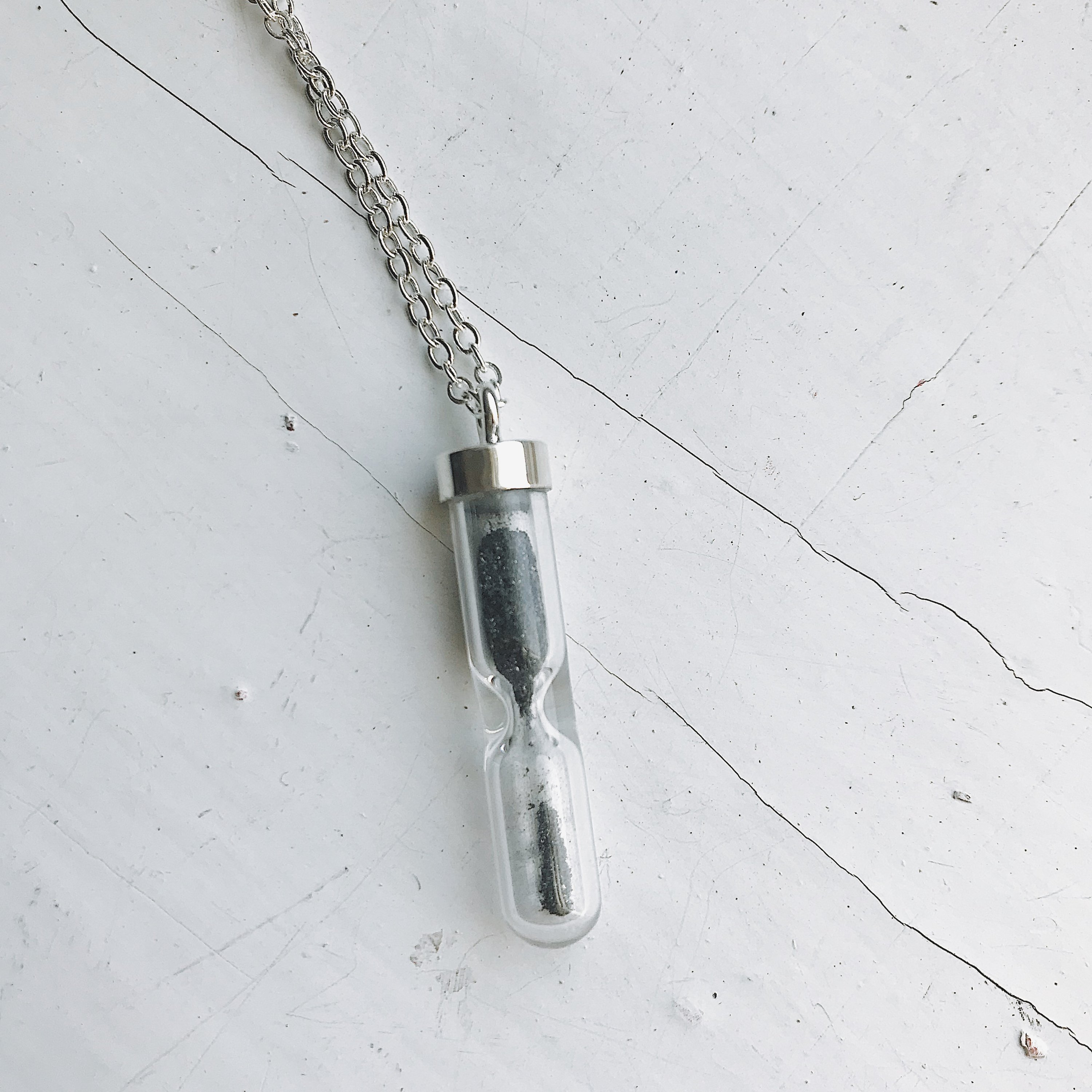 Space Time Hourglass Necklace featuring a clear pendant with authentic meteorite dust, elegantly designed with a sterling silver chain.