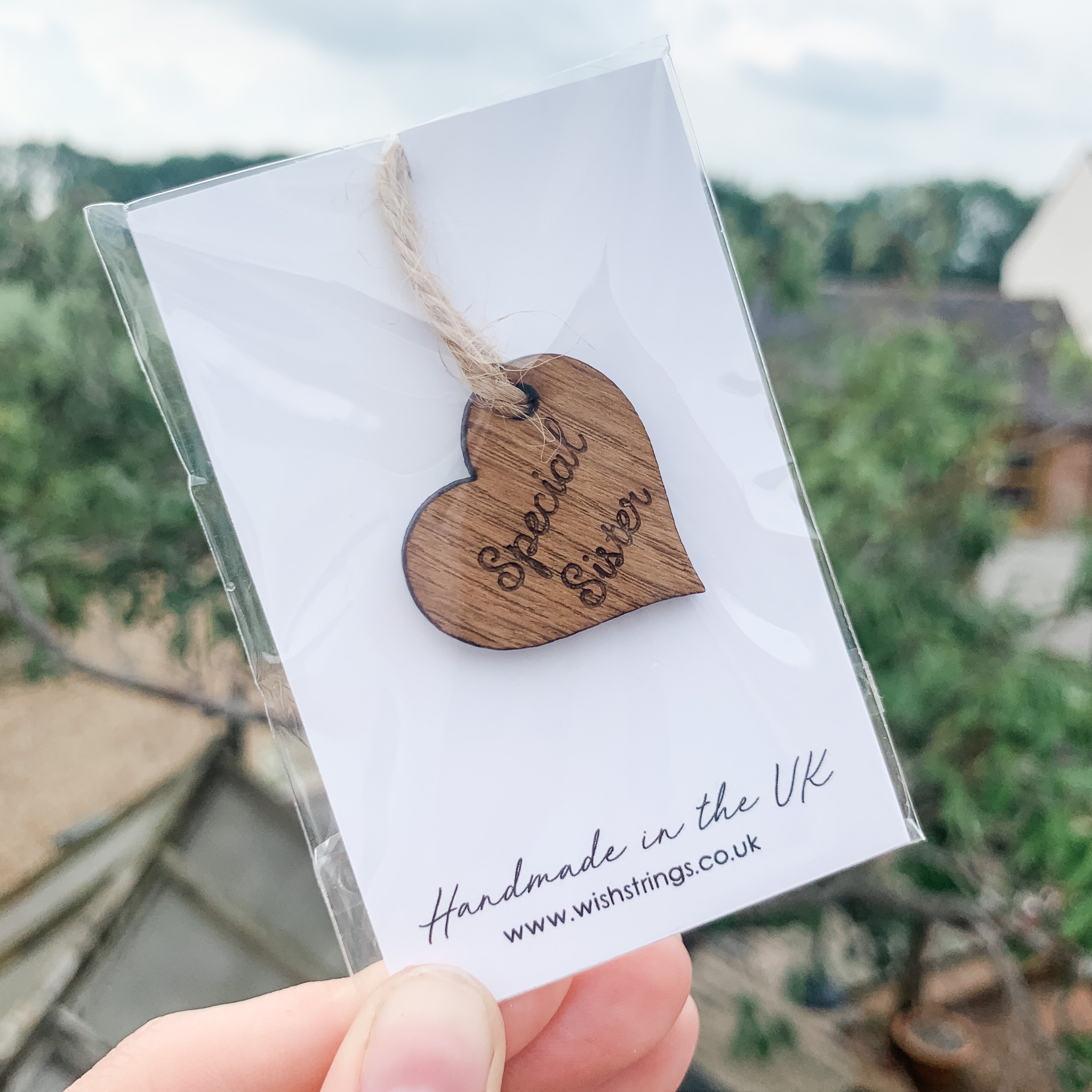 Handmade wooden keyring token for sisters, crafted from oak veneer with a silky smooth finish, presented on a decorative card.