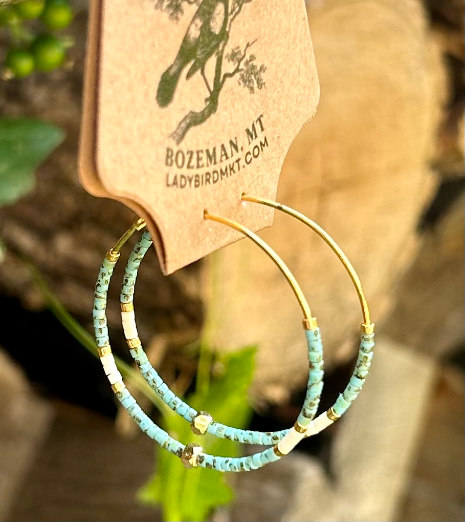 A pair of vibrant speckled turquoise and gold beaded hoop earrings featuring Miyuki Delica seed beads on a delicate gold hoop.