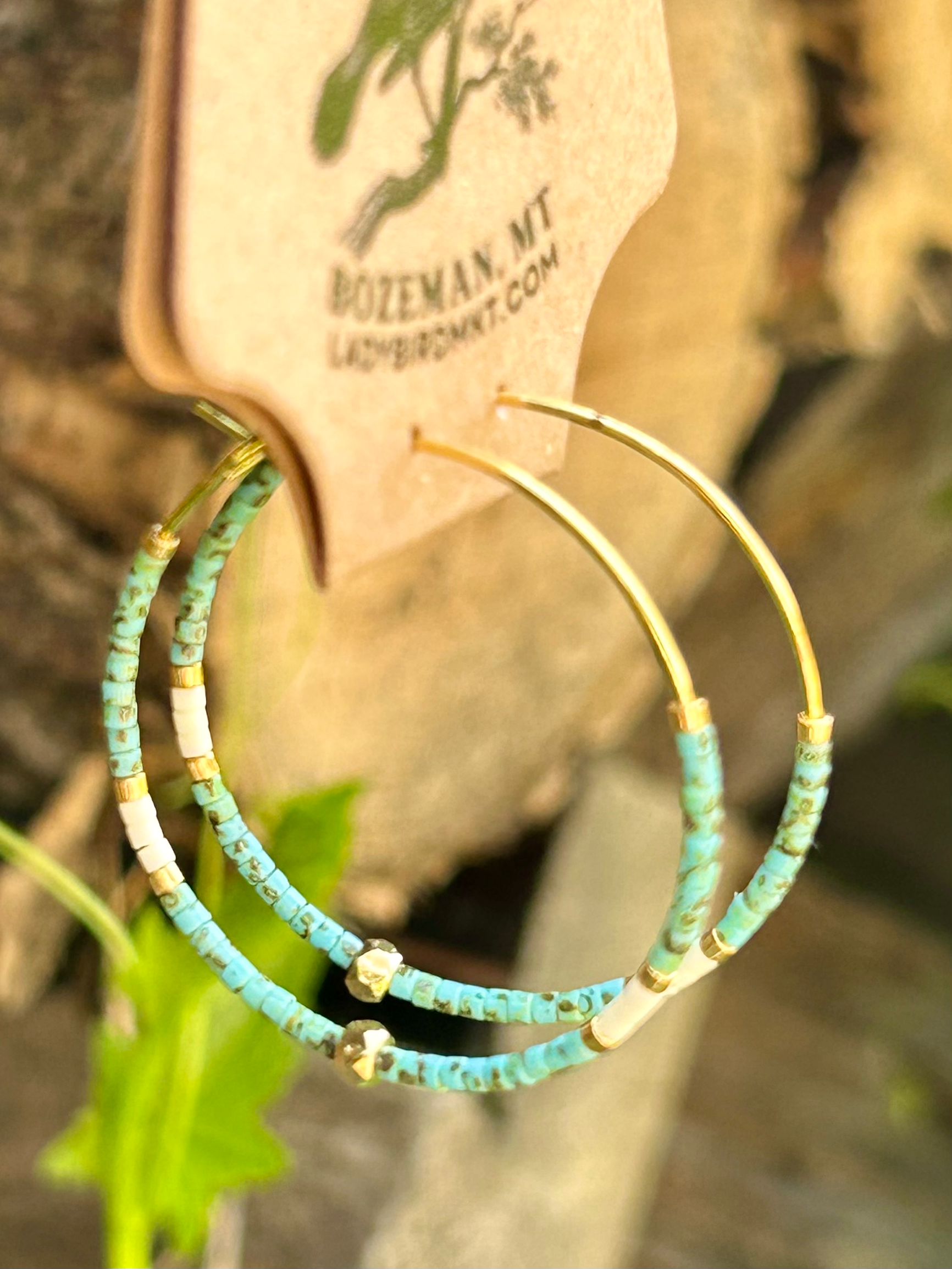 A pair of vibrant speckled turquoise and gold beaded hoop earrings featuring Miyuki Delica seed beads on a delicate gold hoop.