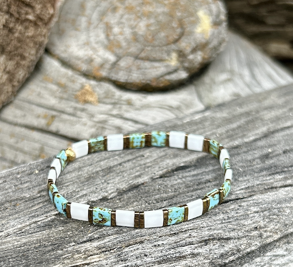 A stylish speckled turquoise bracelet featuring white and gold Tila beads, showcasing a bohemian design.