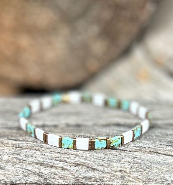 A stylish speckled turquoise bracelet featuring white and gold Tila beads, showcasing a bohemian design.