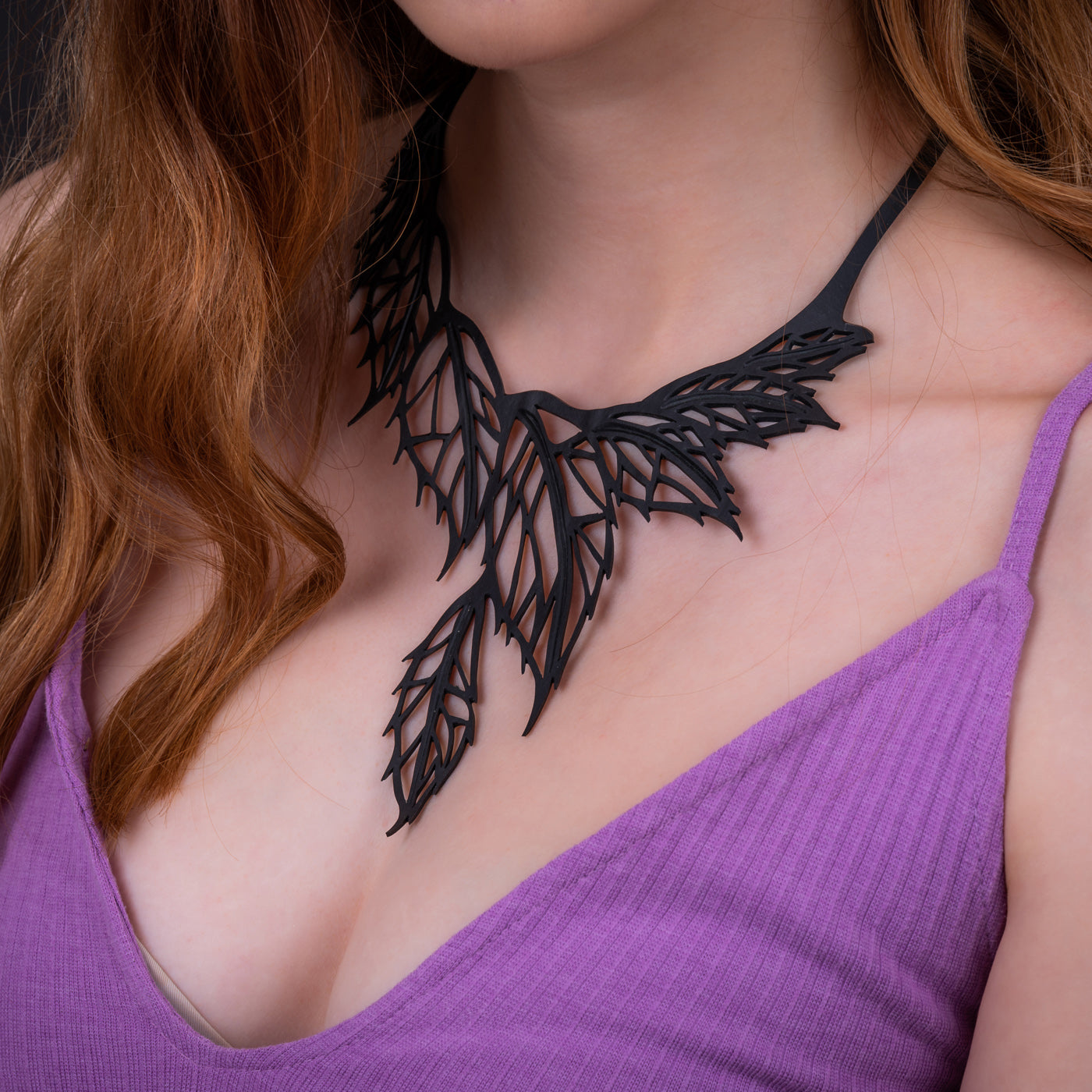 A handcrafted Spring Leaf Recycled Rubber Necklace made from upcycled materials, featuring a unique design and a durable inner tube cord.