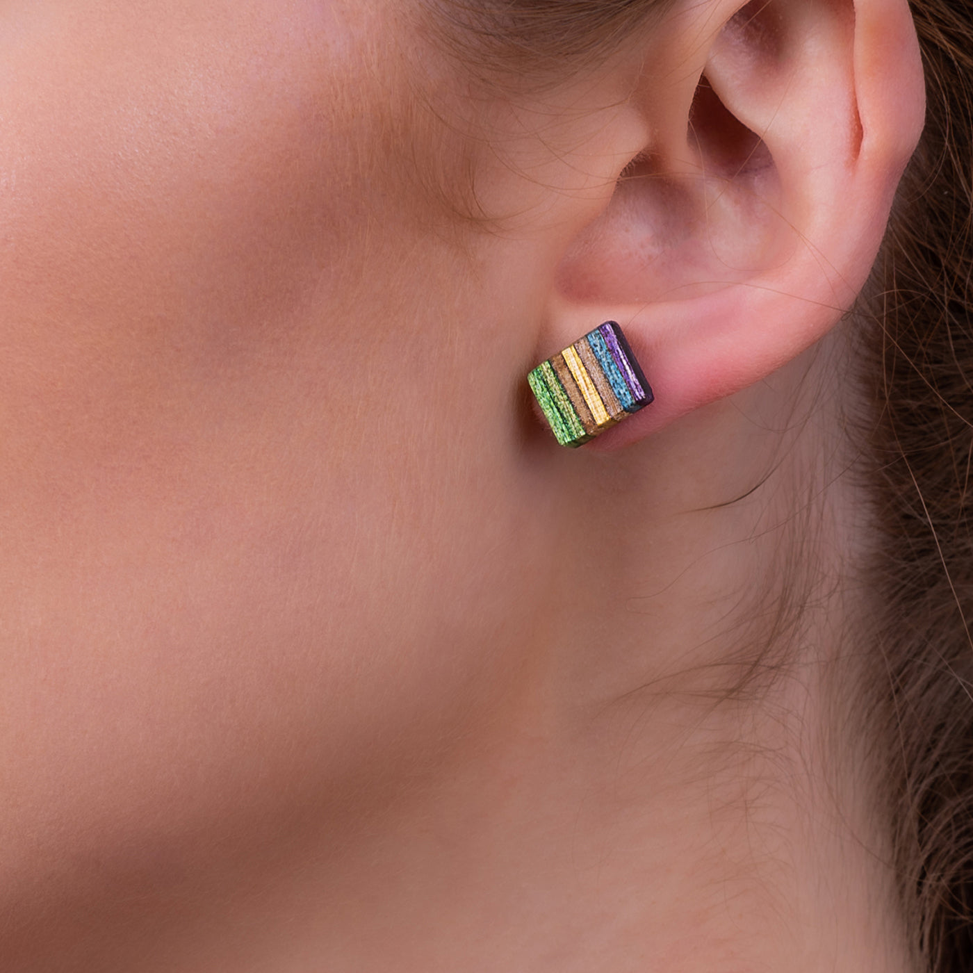 Colorful square stud earrings made from recycled skateboard wood, showcasing unique patterns and textures.