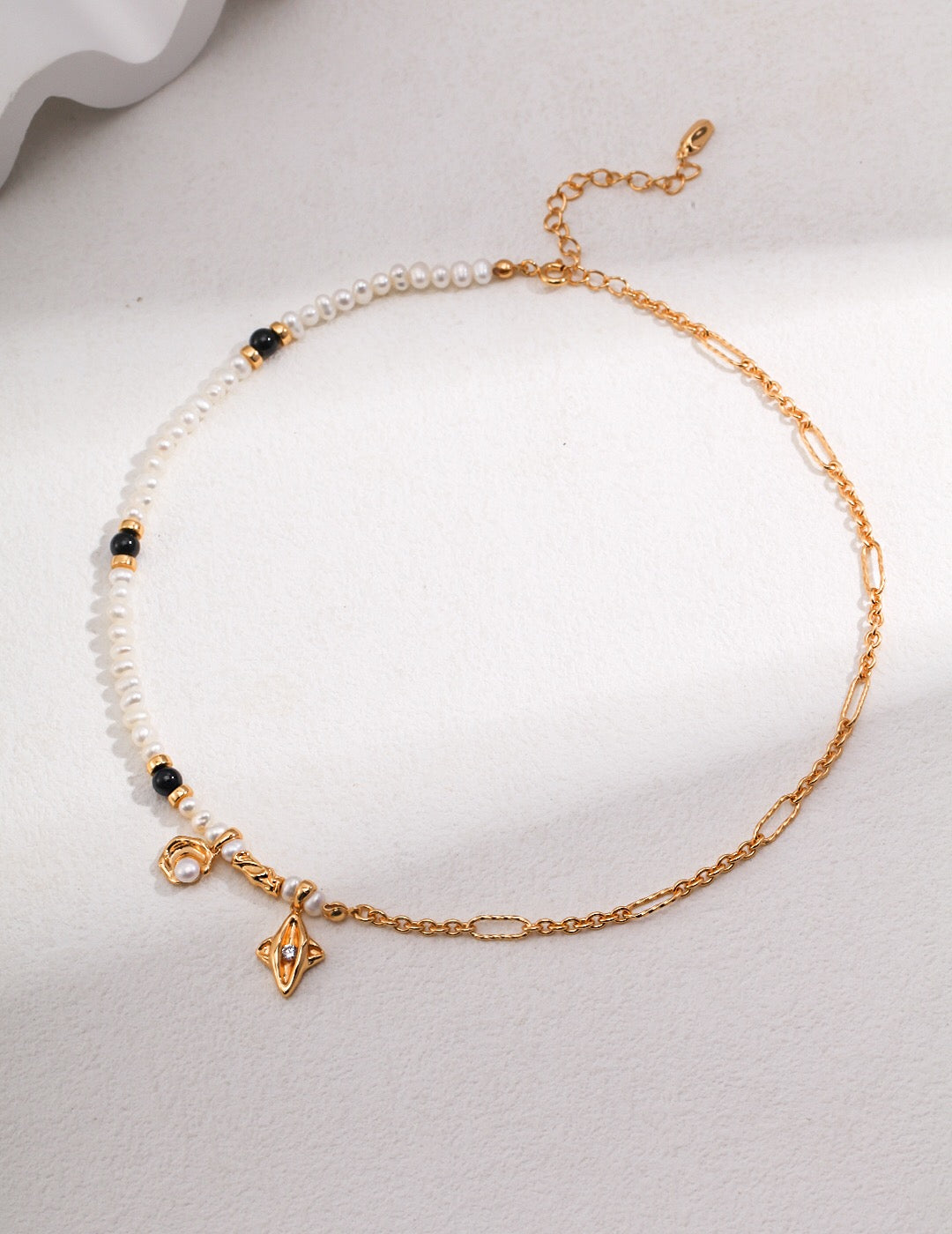 Star and Moon Design Pearl Necklace featuring natural pearls, black agate, and gold vermeil, elegantly displayed on a soft background.