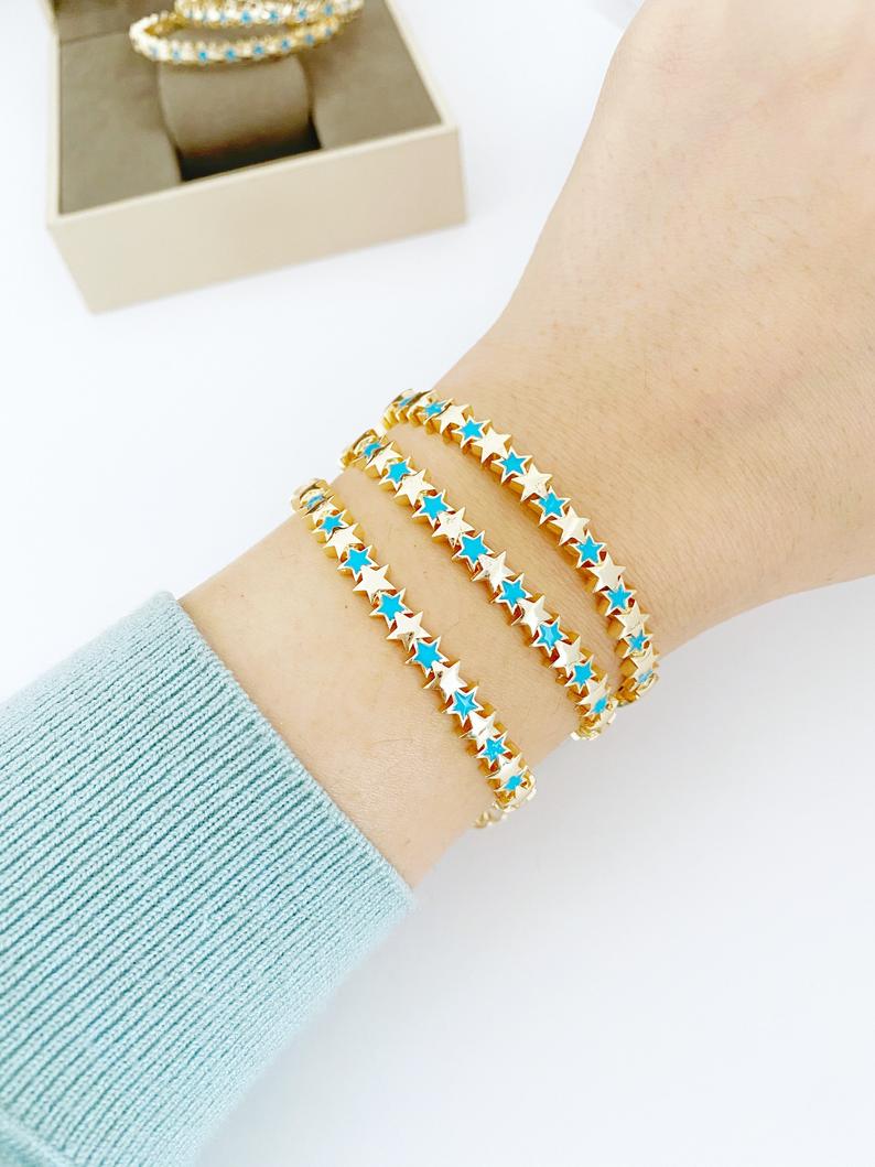 A beautiful gold cuff bracelet featuring a turquoise star charm, showcasing its adjustable design and elegant craftsmanship.