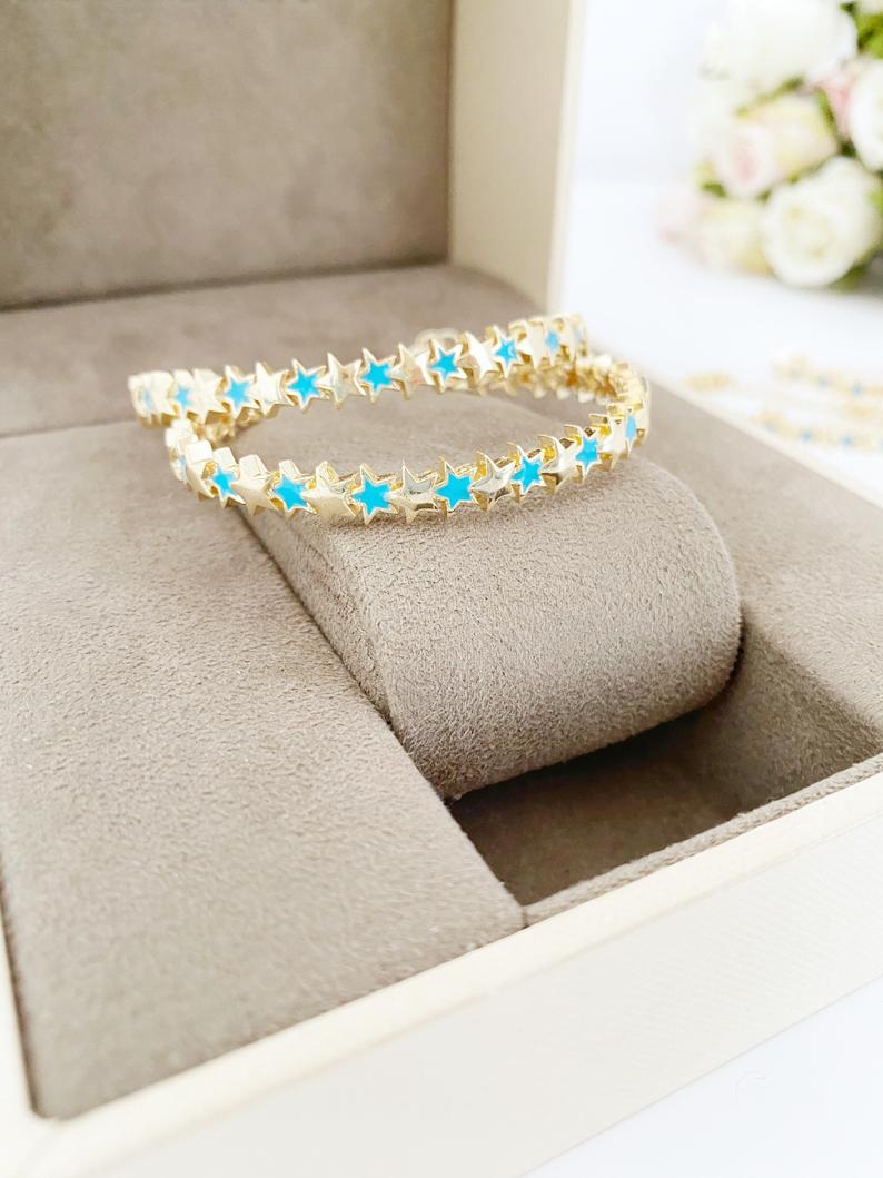 A beautiful gold cuff bracelet featuring a turquoise star charm, showcasing its adjustable design and elegant craftsmanship.