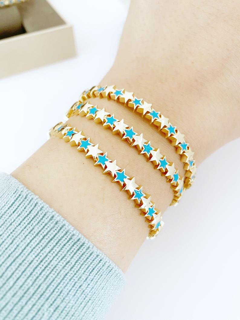 A beautiful gold cuff bracelet featuring a turquoise star charm, showcasing its adjustable design and elegant craftsmanship.