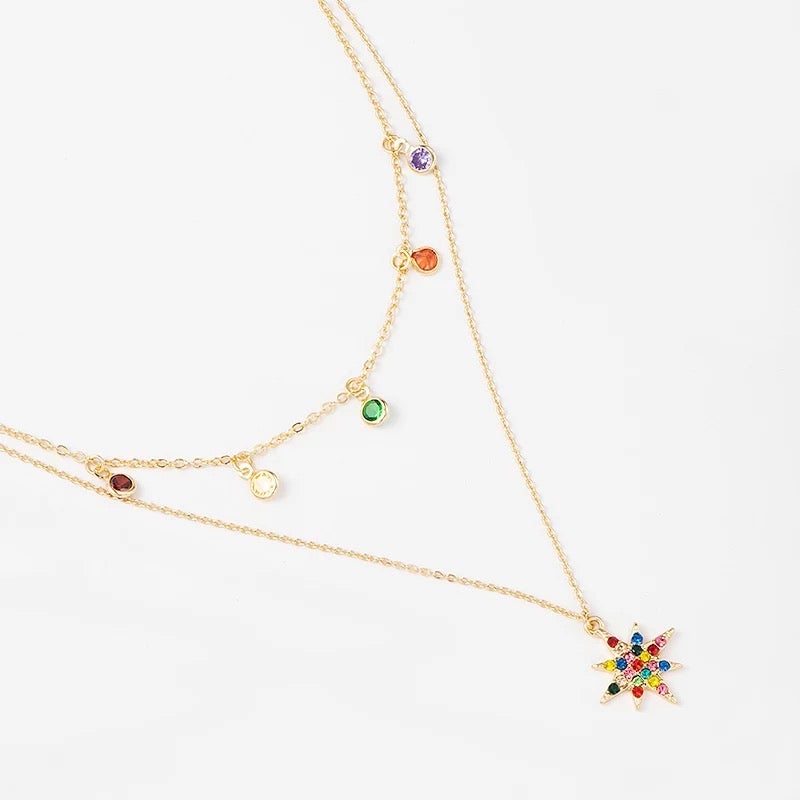 A layered star necklace adorned with rainbow cubic zirconia stones, featuring a gold-plated finish and adjustable chain.