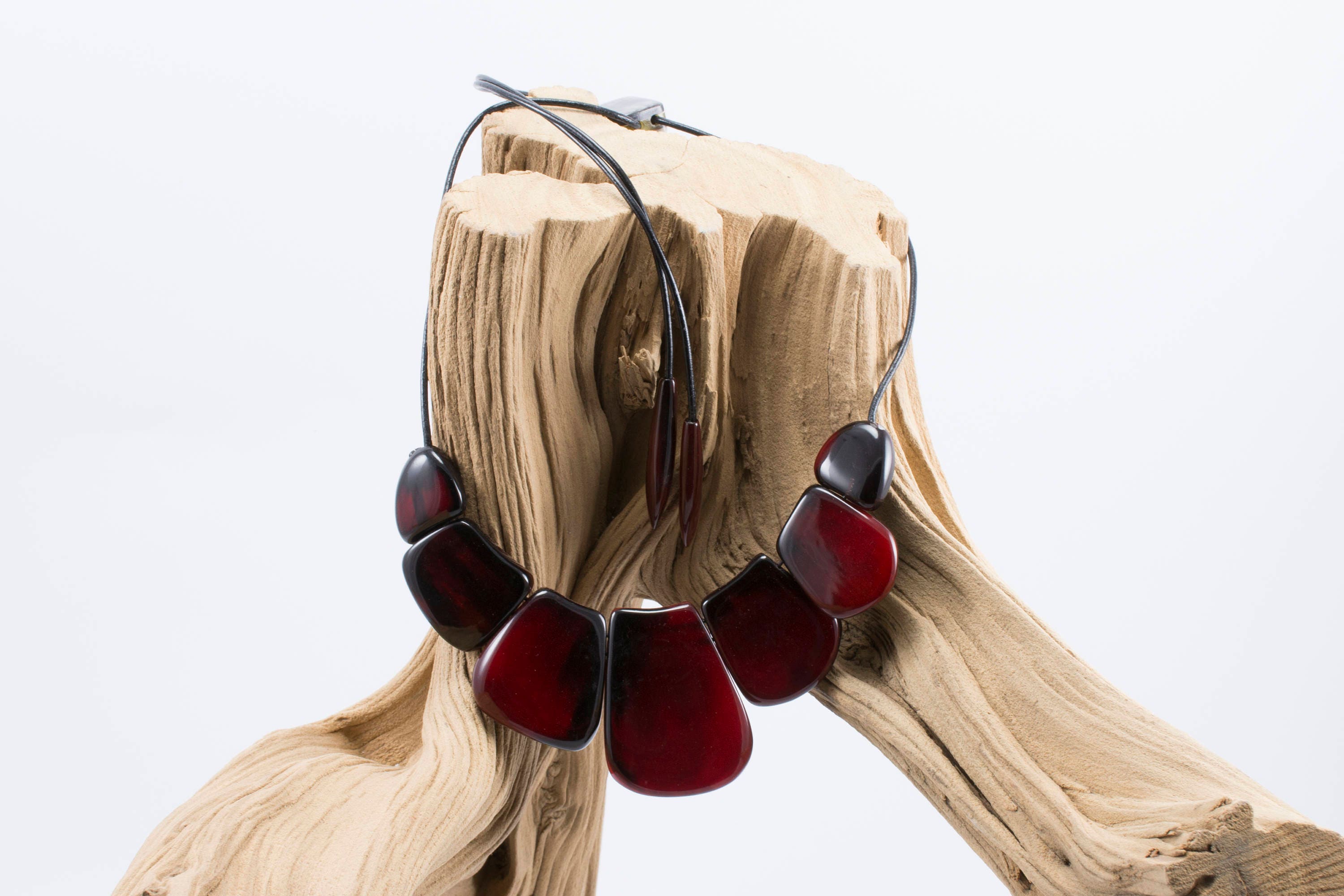 A vibrant statement red necklace made of natural horn, featuring smooth volumetric ovals and a leather cord with teardrop ends.